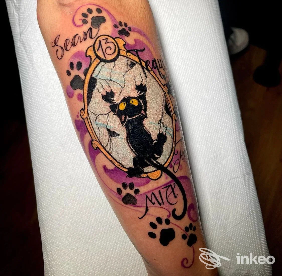 Tatuaggio su avambraccio con gatto nero in specchio incrinato, impronte e dettagli viola - Scribble Tattoo, Lucca.