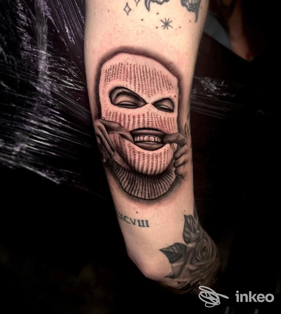 Tatuaggio su avambraccio con volto mascherato che sorride, dettaglio di shading e linework – Sorry Mom Tattoo Livorno, Livorno.