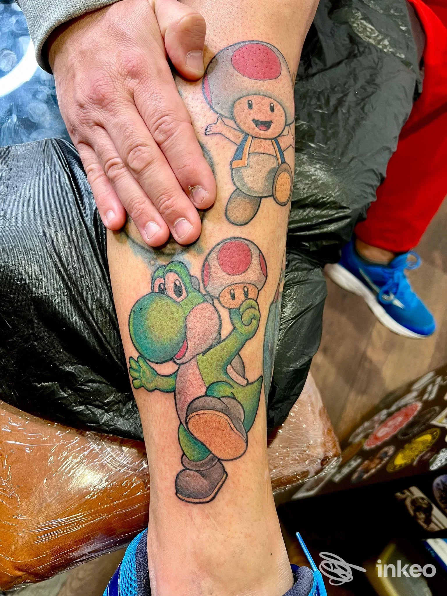 Tatuaggio colorato su gamba con Yoshi e due Toad, foto inviata da Studio tattoo BigEd a Grosseto, primo piano del polpaccio.