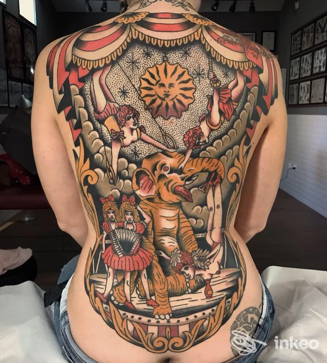 Grande tatuaggio sulla schiena a tema circense, eseguito da Tattoo Circus a Bientina, con elefante e artiste in colori caldi.