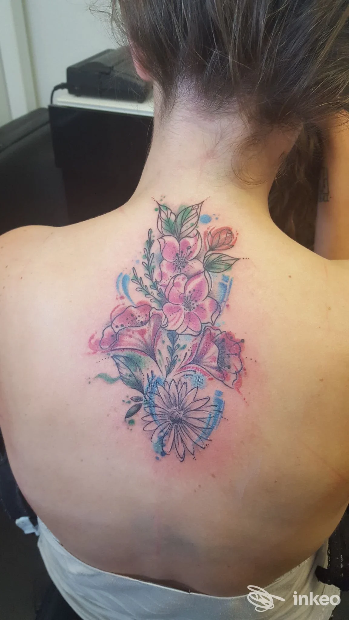 Tatuaggio floreale acquerello sulla parte superiore della schiena e nuca, lavoro eseguito da Tattoo Shop 669 a Grosseto.