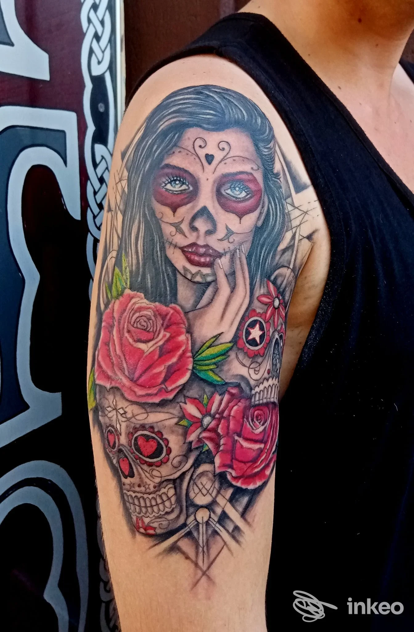 Tatuaggio colorato a tema sugar skull con rose rosse sul braccio superiore, Tattoo e Piercing Studio Pisa, Pisa.