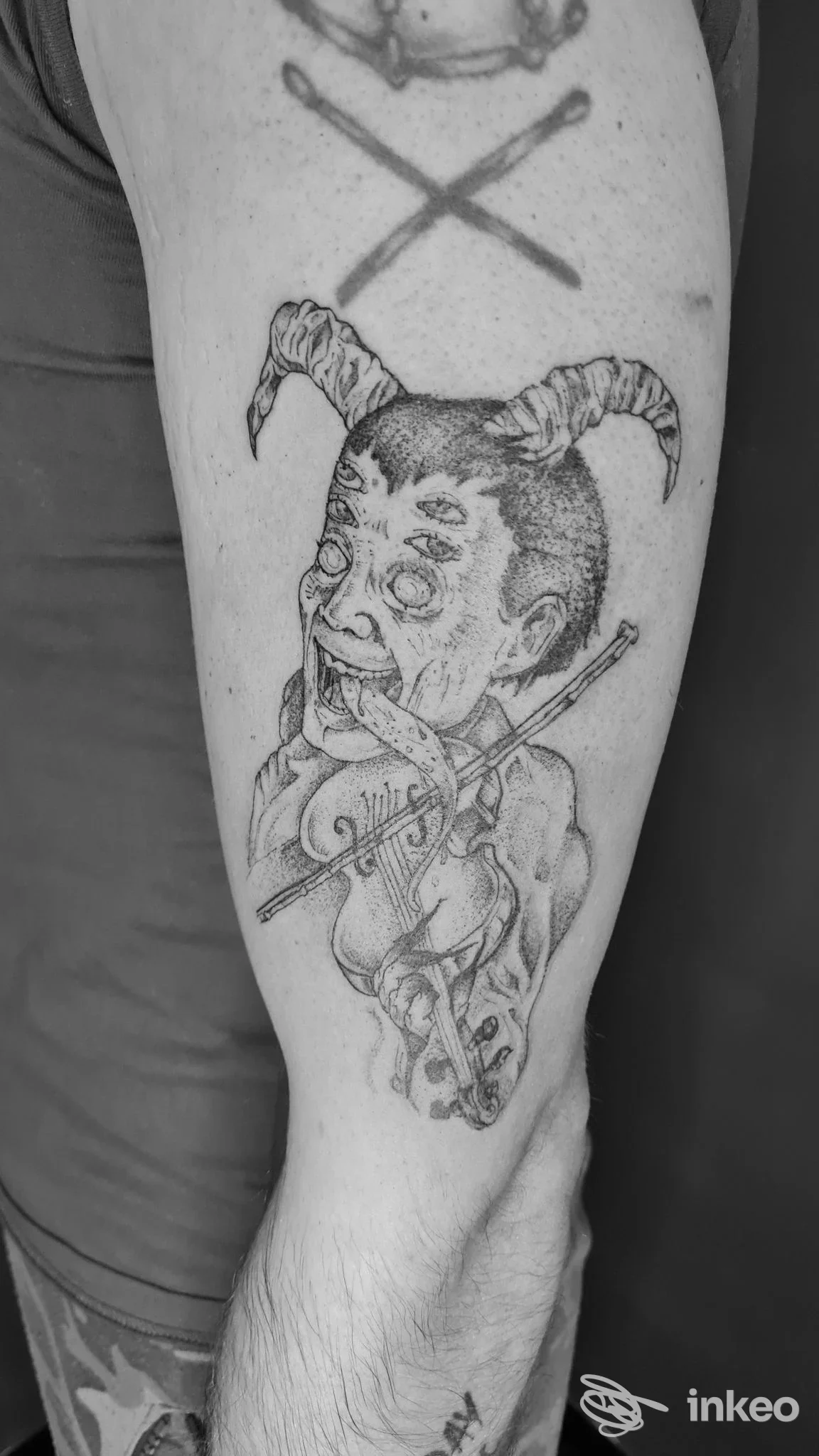 Tatuaggio su avambraccio raffigurante una figura con corna che suona un violino — Tattoo Shop, Massa.