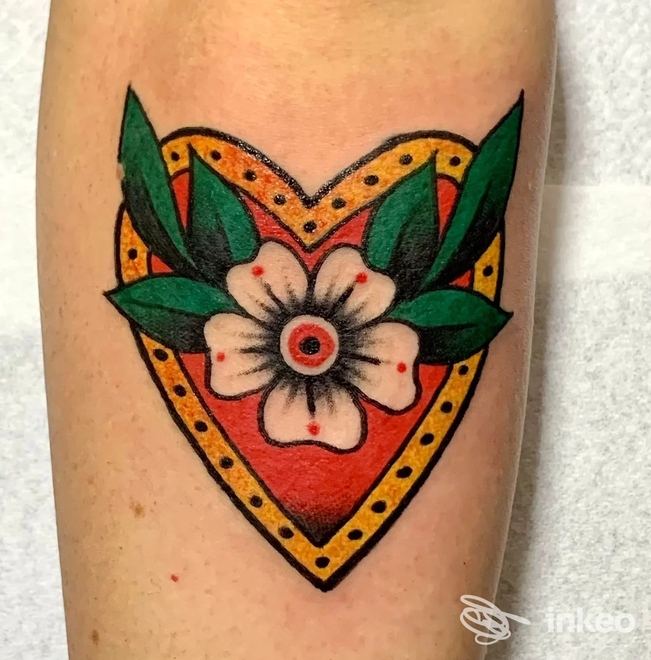 Tatuaggio tradizionale a forma di cuore con fiore centrale sul braccio, realizzato da The Black Belt Tattoo a Viareggio.