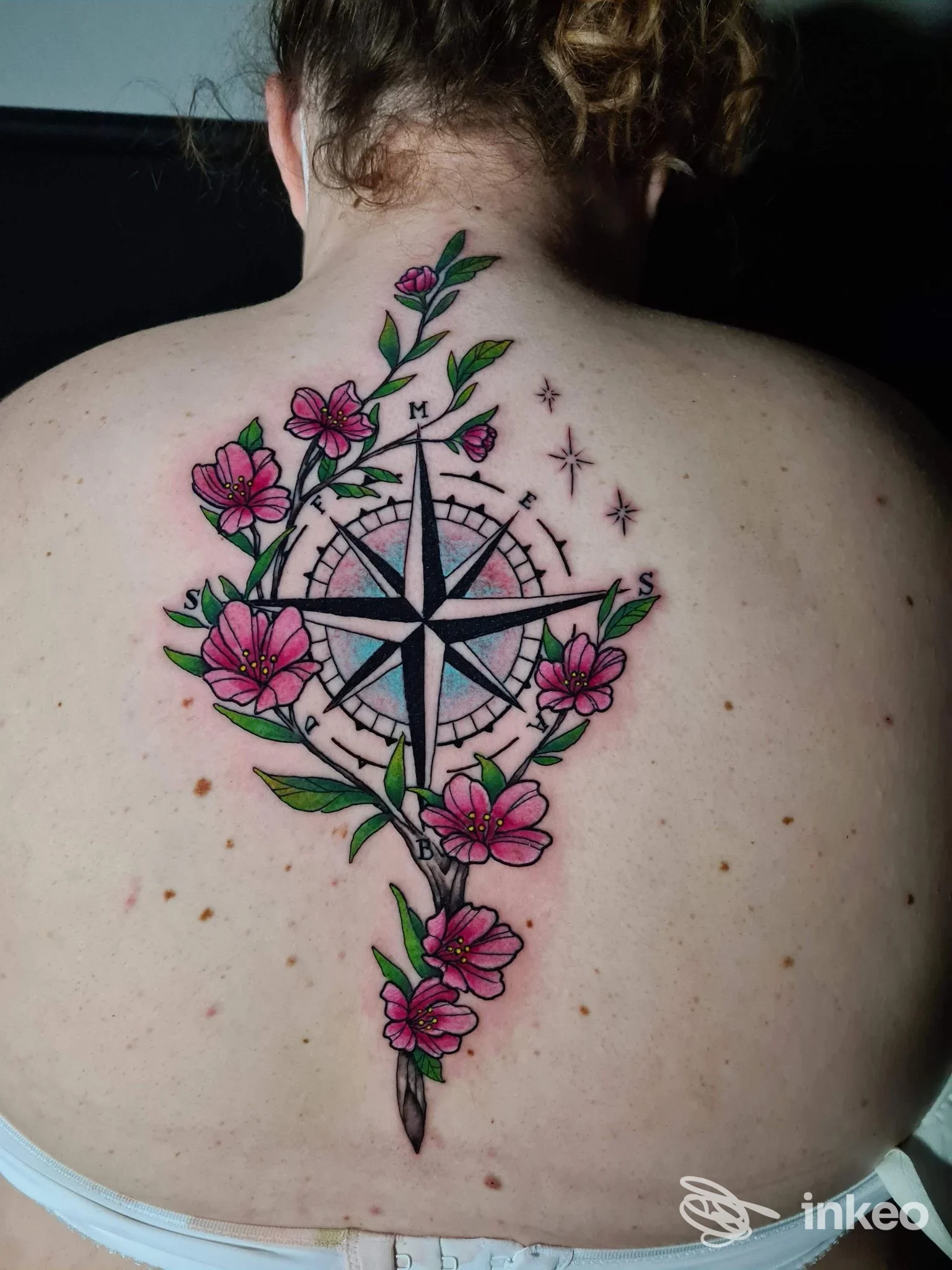 Grande tatuaggio a bussola e fiori rosa sulla schiena superiore di una cliente, fotografato per TheSacredInk by leletattoo a Viareggio.