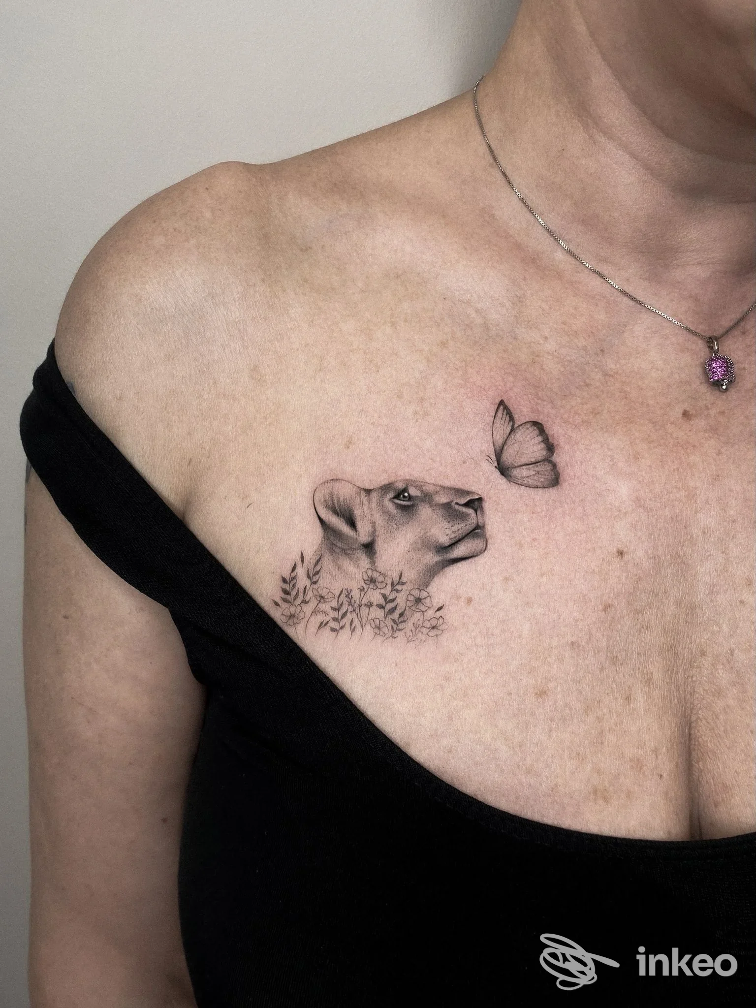 Piccolo tatuaggio realistico in bianco e nero di testa di felino e farfalla sullo sterno, appena sotto la clavicola; foto dallo studio ATTITUDE Tattoo Studio a Massa.