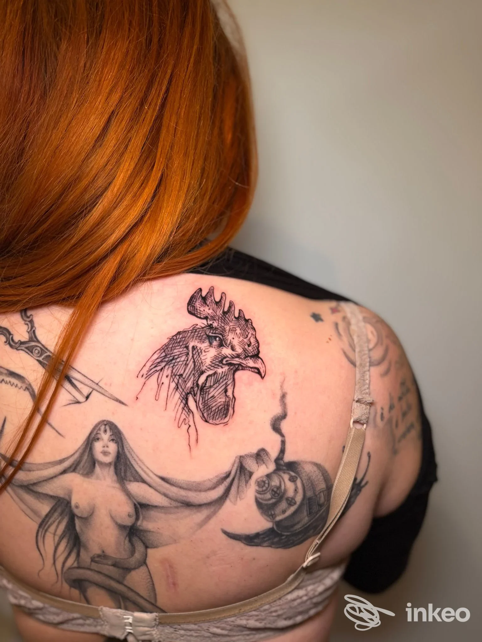 Spalla e parte alta della schiena tatuate con testa di gallo e figura femminile, foto di Adne Tattoo, Firenze.