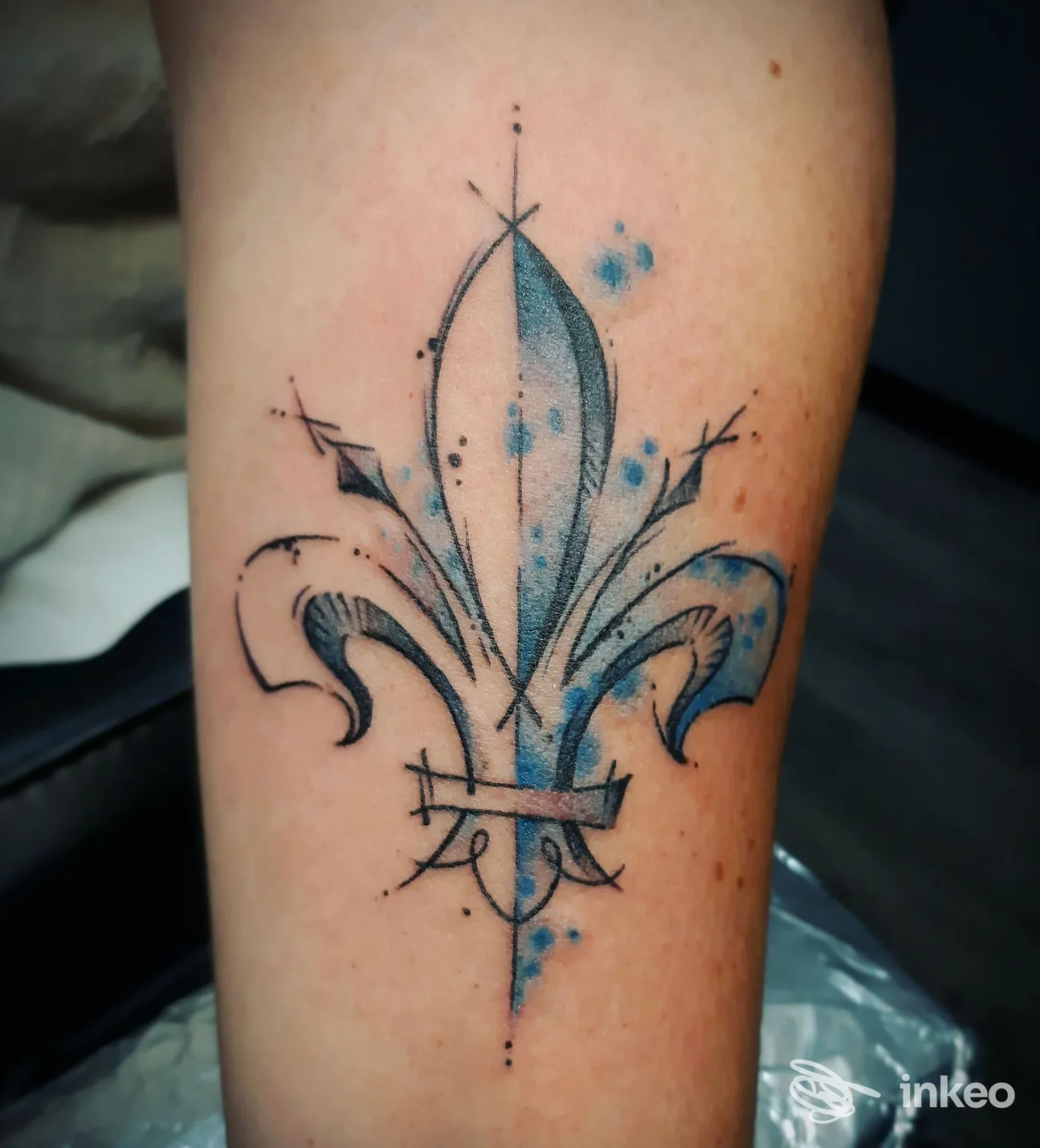 Tatuaggio a giglio stilizzato blu e nero sull'avambraccio, foto fornita da Trick'r Treat Tattoo Studio, Firenze.