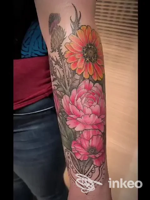 Avambraccio con ampio tatuaggio floreale colorato: rose rosa, margherita arancione, foglie e ornamento grafico. Trick'r Treat Tattoo Studio, Firenze.