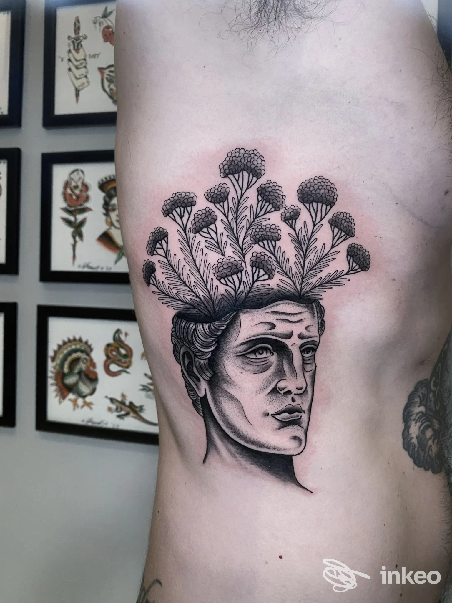 Tatuaggio sul fianco sinistro con volto classico che si trasforma in fiori stilizzati, fotografato nello studio White Dog Classic Tattoo, Arezzo.