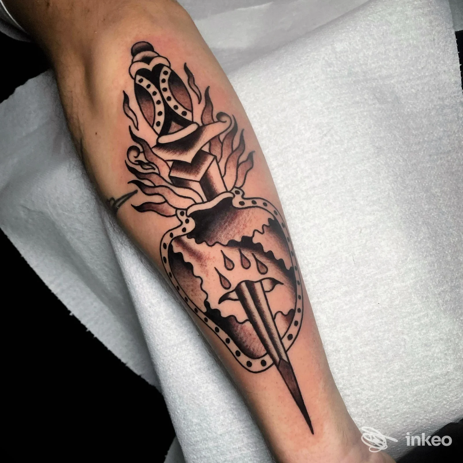 Tatuaggio su avambraccio: pugnale che trafigge un cuore con fiamme. Foto dello studio White Dog Classic Tattoo, Arezzo.