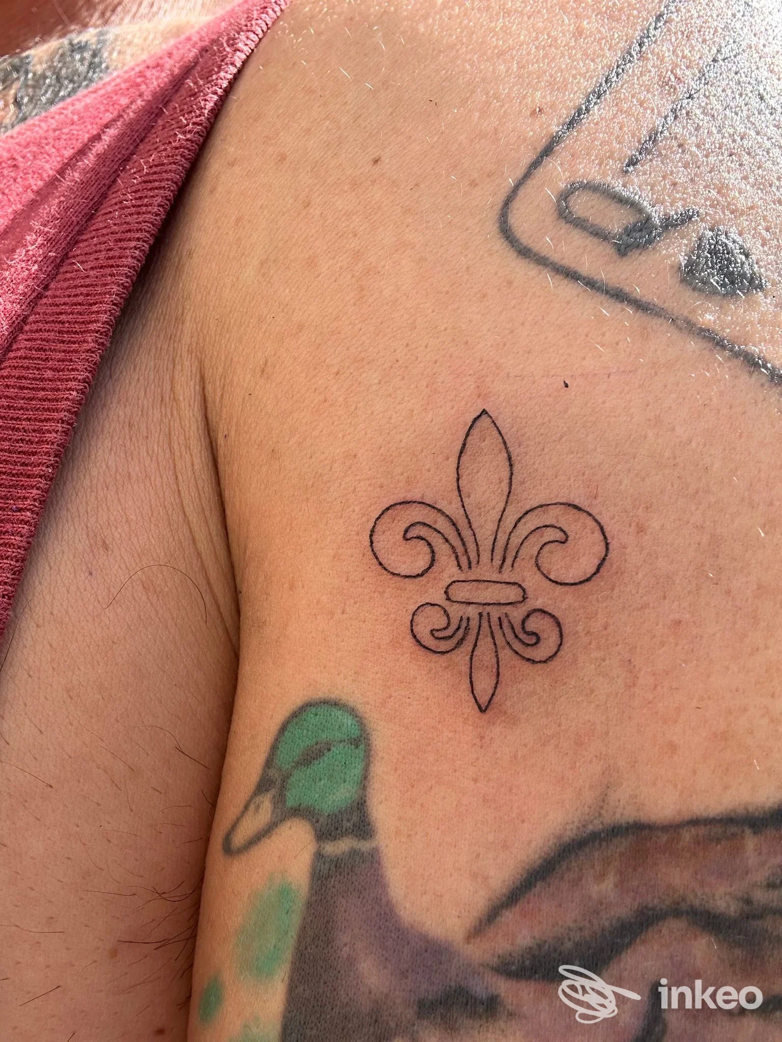Tatuaggio a linework di una fleur-de-lis sulla spalla, foto inviata dallo studio Youcore Tattoo a Firenze.