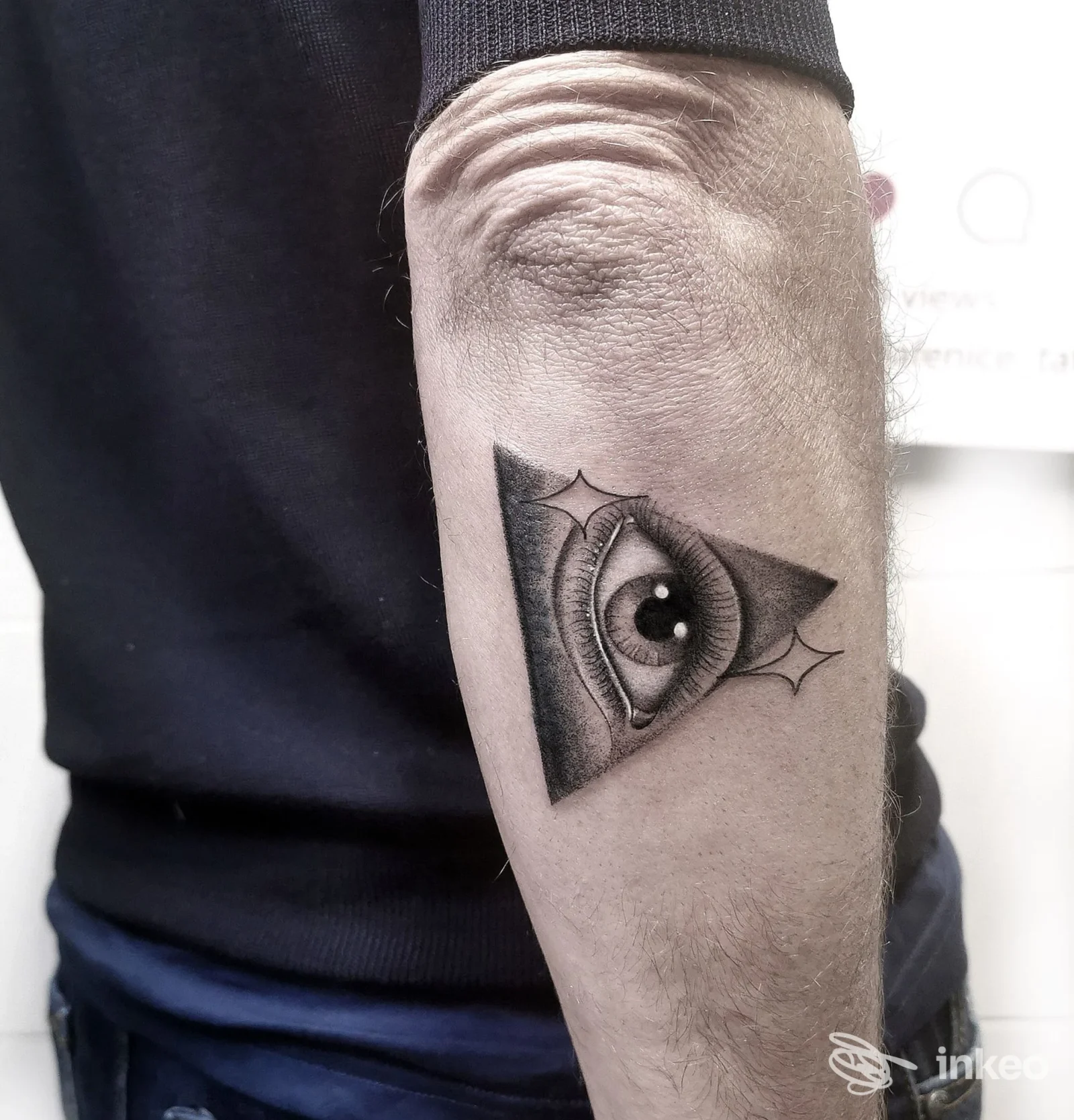 Tatuaggio a occhio stilizzato dentro un triangolo sull'avambraccio, eseguito presso ARABA FENICE, San Miniato.