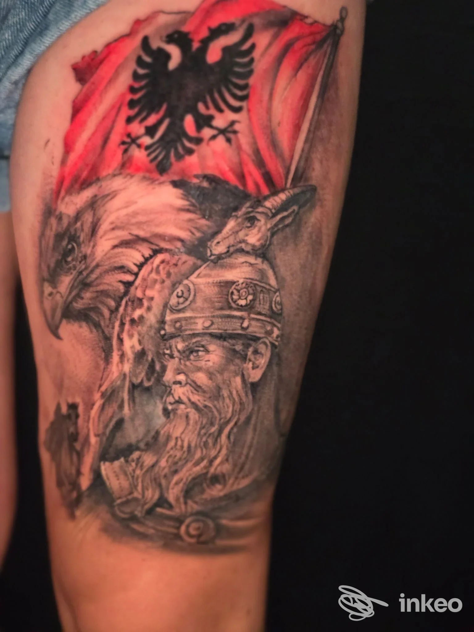 Tatuaggio su braccio con aquila, volto di guerriero e bandiera rossa, realizzato da Alex Tattoo a Lucca.