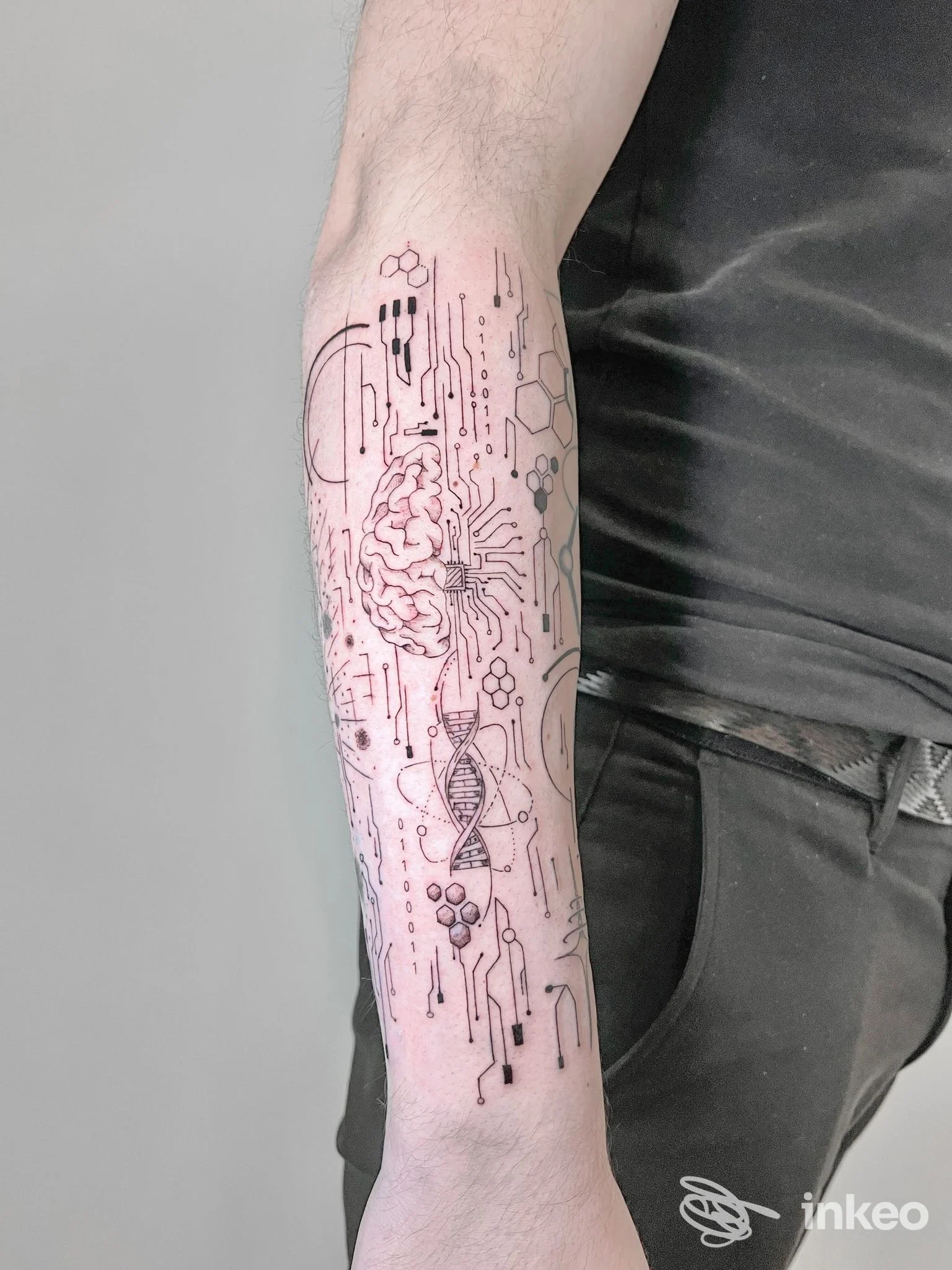 Tatuaggio su avambraccio con motivi a circuito, cervello stilizzato ed elica, fotografia pubblicata da Amnèsia Tattoo Lab, Pistoia.