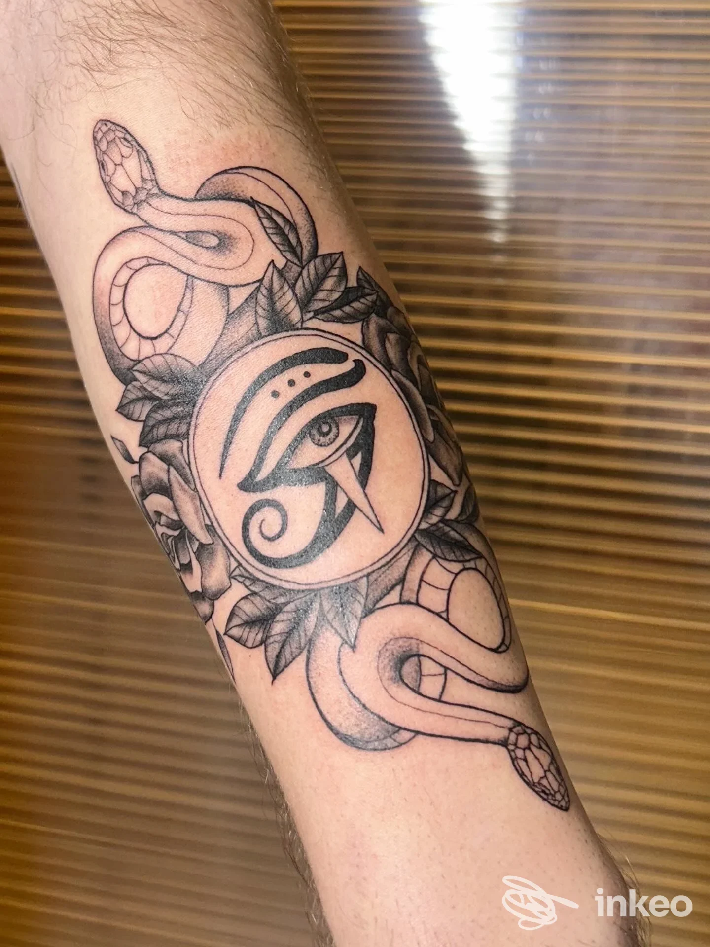 Tatuaggio sull'avambraccio con serpente avvolto e occhio stilizzato, eseguito da Amuleto Ritual Tattoo a Firenze.