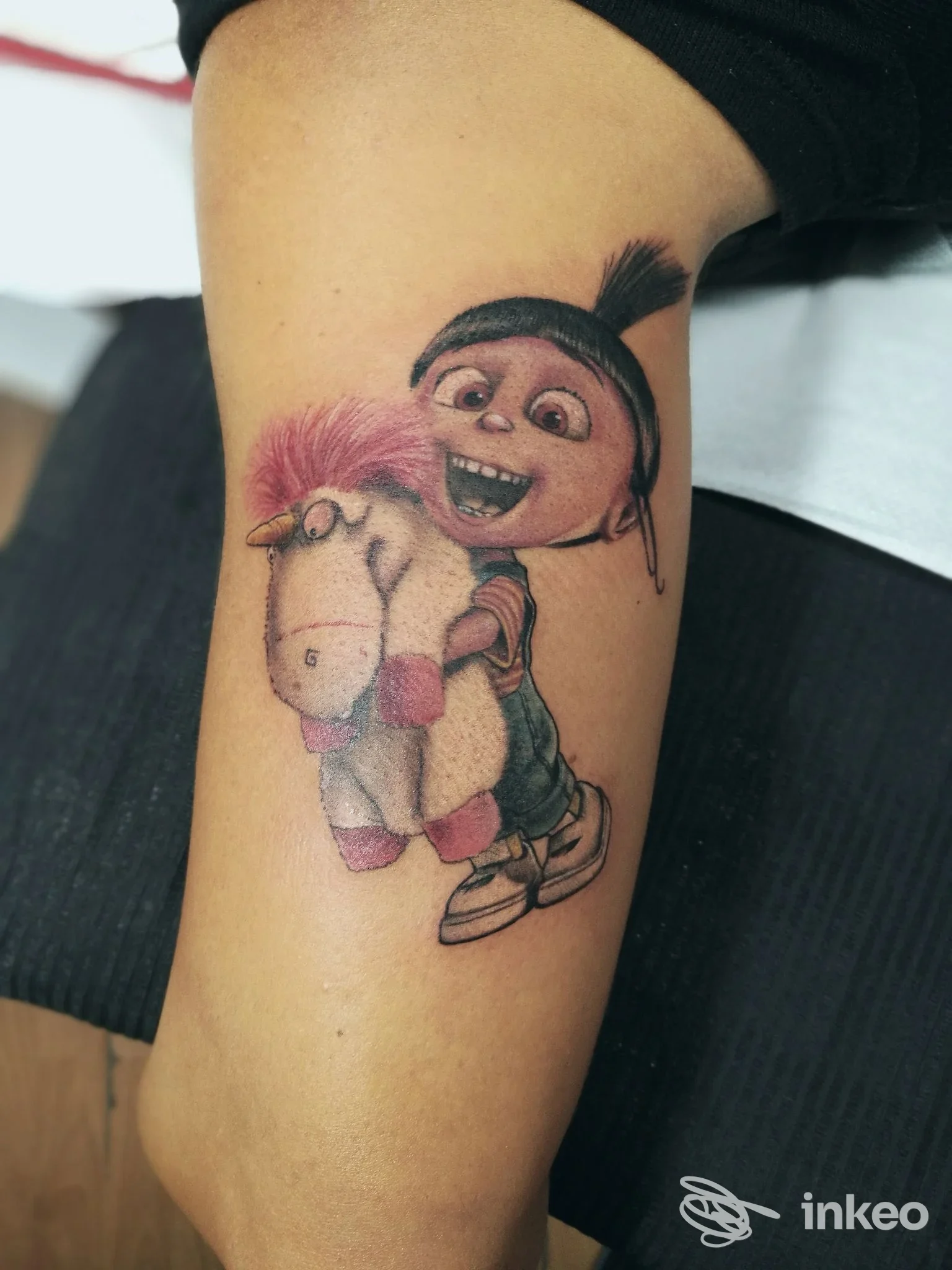 Tatuaggio a colori su coscia con personaggio cartoonesco che abbraccia un peluche, foto fornita da AnimaTinta tattoo shop, Pontedera.