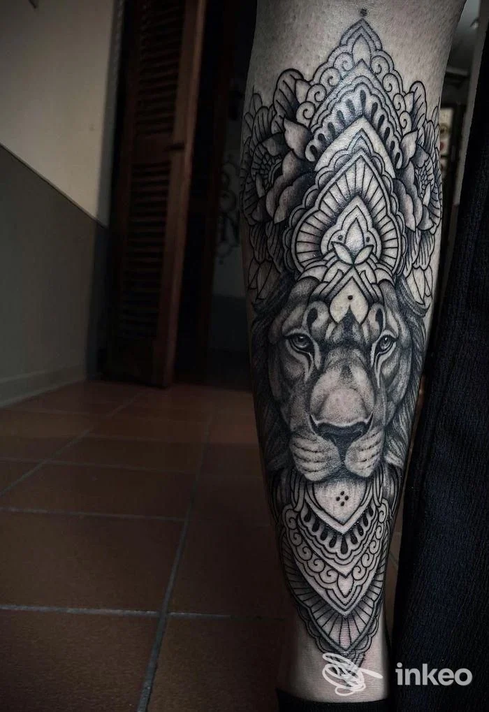 Dettagliato tatuaggio su avambraccio con testa di leone e decorazioni mandala, realizzato da Barbanera Tattoo Shop a Navacchio.