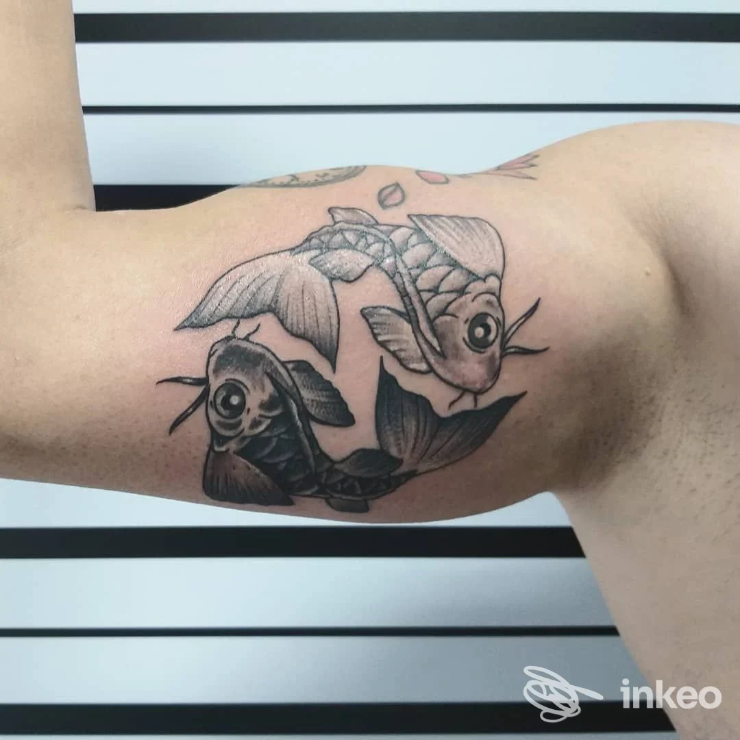 Tatuaggio di due carpe koi sul bicipite, realizzato da Be Honest Tattoo di Simona Sii Onesto a Cecina.