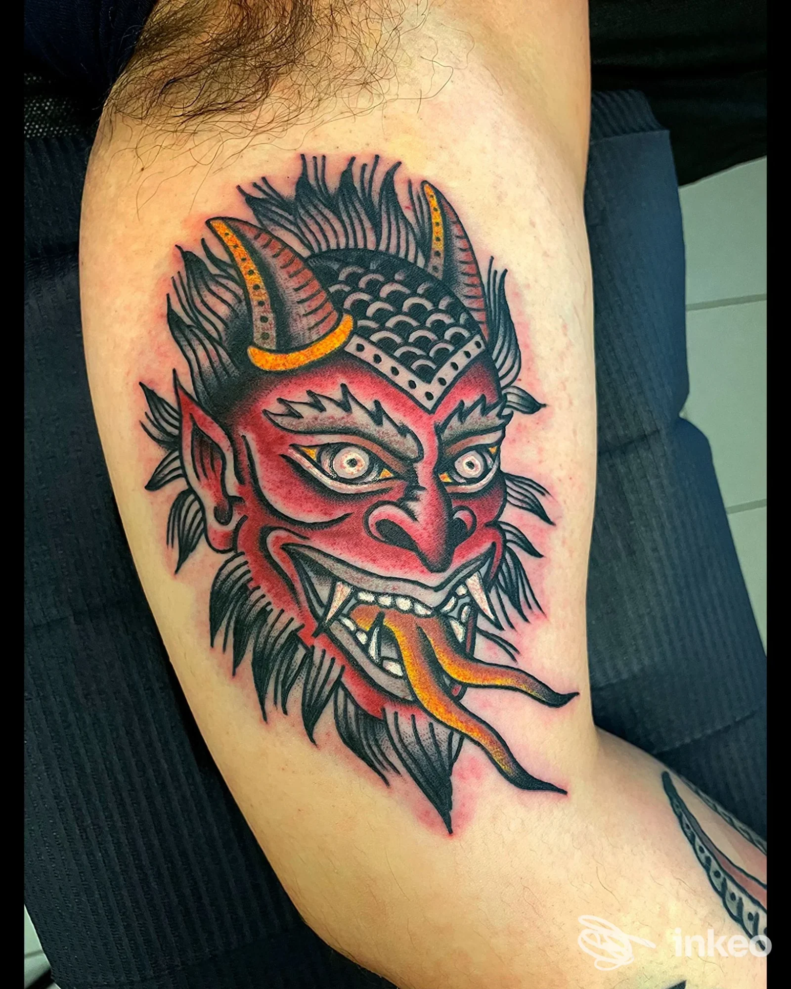Tatuaggio testa demoniaca a colori sul bicipite interno, foto fornita da Black Circle Hellectric Tattooing, Figline Valdarno.