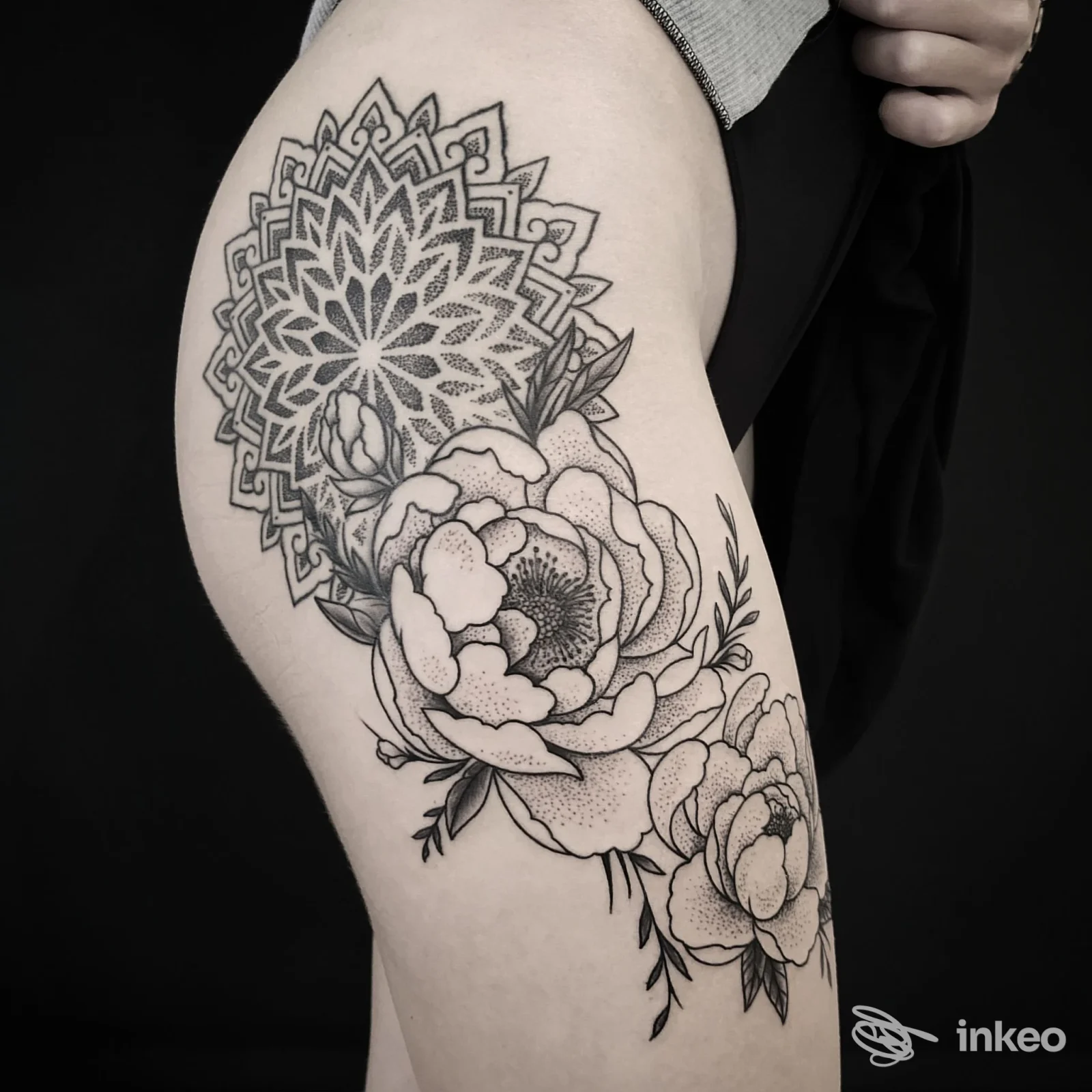 Grande tatuaggio in bianco e nero con mandala e peonie sulla coscia, fotografia della realizzazione di Blackbindu Tattoo & Art a Volterra.