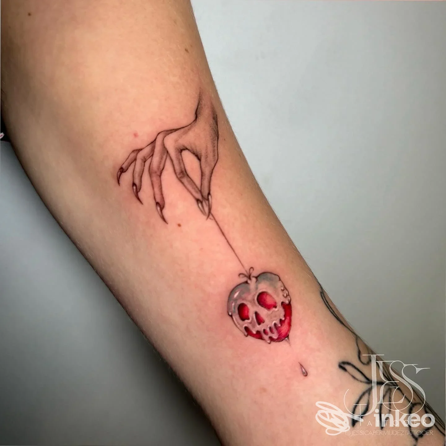Tatuaggio su avambraccio raffigurante una mela con teschio e una mano che la trattiene, Bocanegra Tattoo Piercing Studio, Siena.