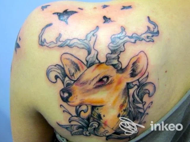 Tatuaggio a colori su spalla raffigurante un cervo stilizzato con corna decorative, foto fornita da Cherry Bloom Tattoo, Fornaci di Barga.