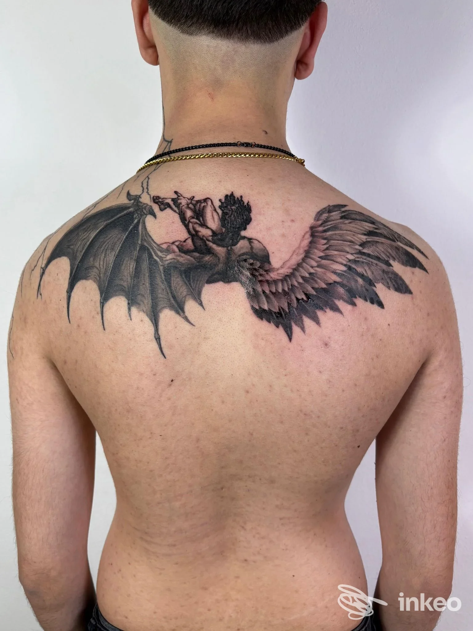 Ampio tatuaggio in bianco e nero sulla parte superiore della schiena, foto fornita da DAMA TATTOO STUDIO, Vada.
