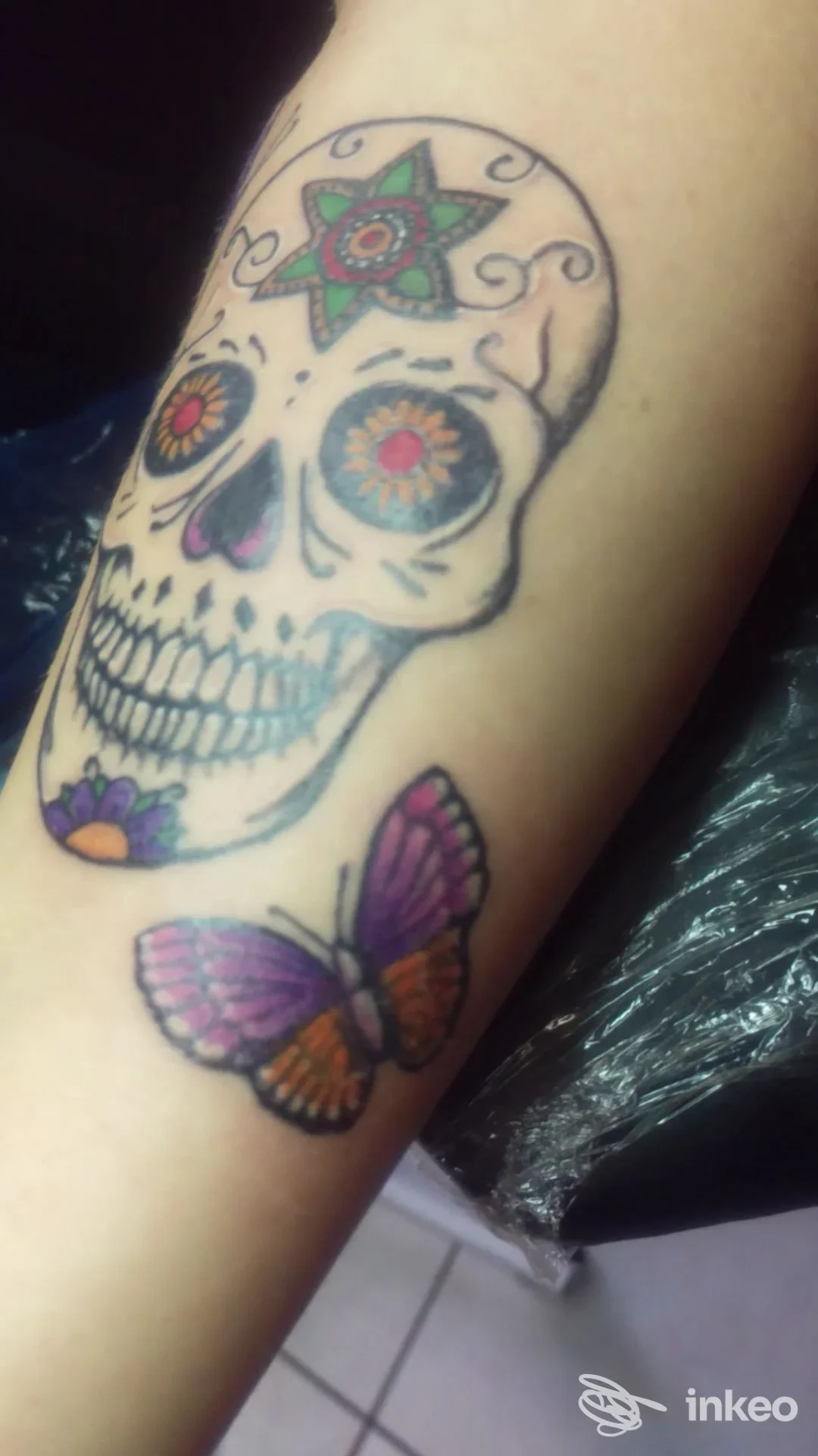 Tatuaggio colorato di un teschio in stile sugar skull e una farfalla sull'avambraccio, Cozmic Tattoo & Piercing, Aulla.