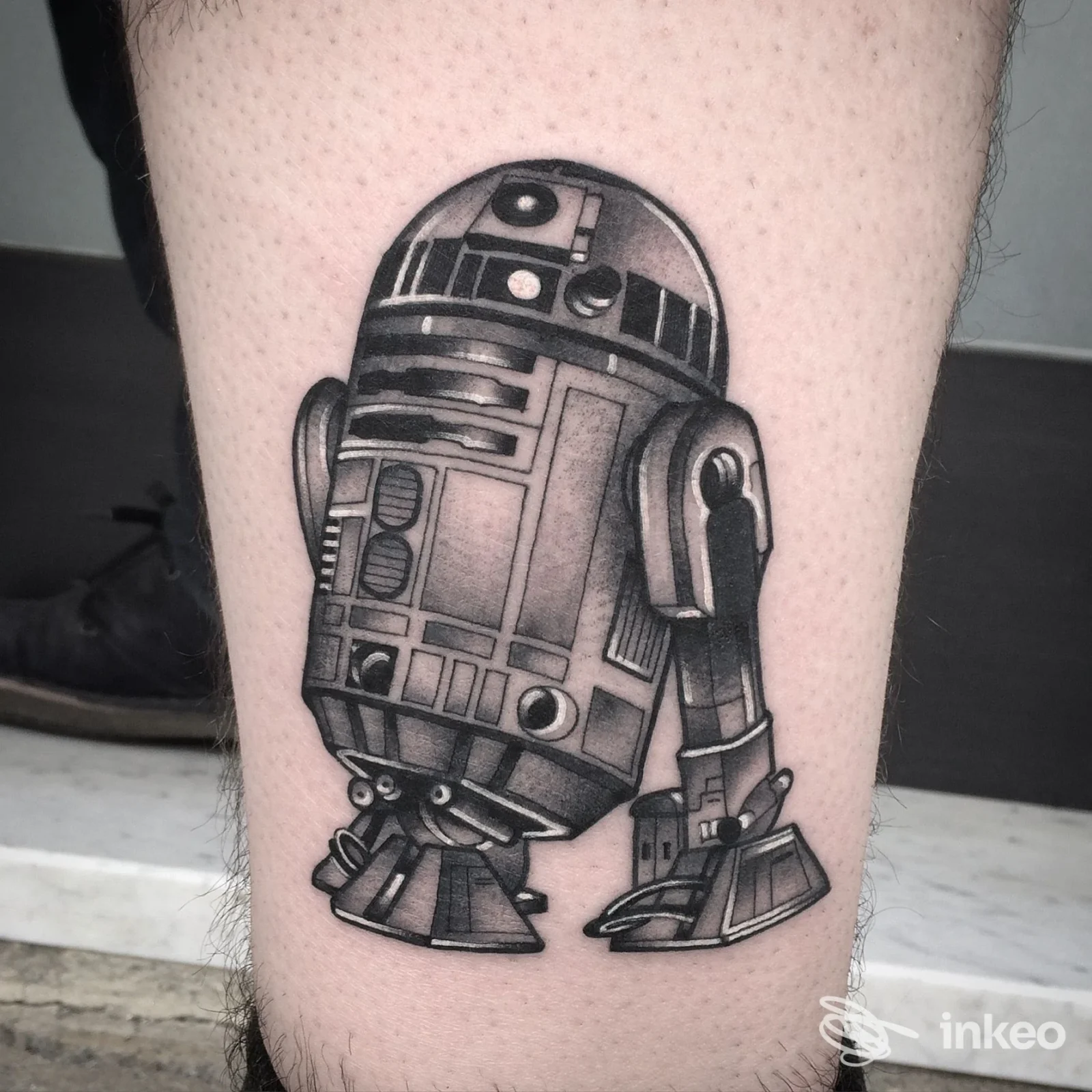 Tatuaggio in bianco e nero di un droide sul polpaccio, El Rana Tattoo Shop, Arezzo.