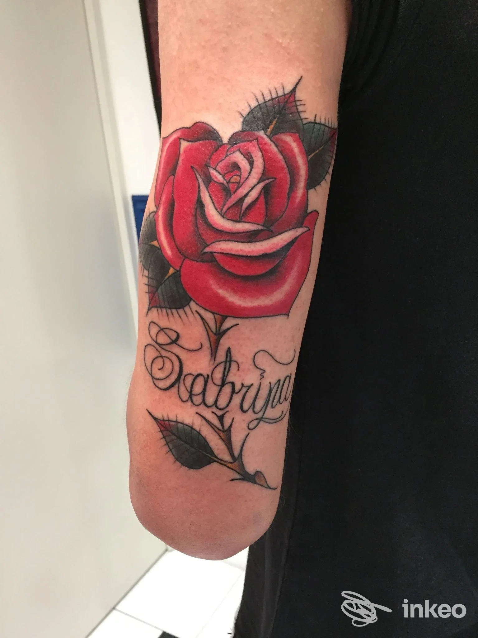 Tatuaggio di una grande rosa rossa con la scritta 'Sabrina' sull'avambraccio, scatto dello studio El Rana Tattoo Shop ad Arezzo.