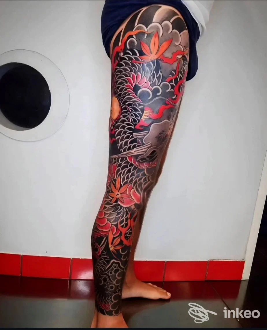 Tatuaggio full sleeve su gamba sinistra con elementi scaglie, nuvole e foglie. Energia Tattoo Studio, Livorno.