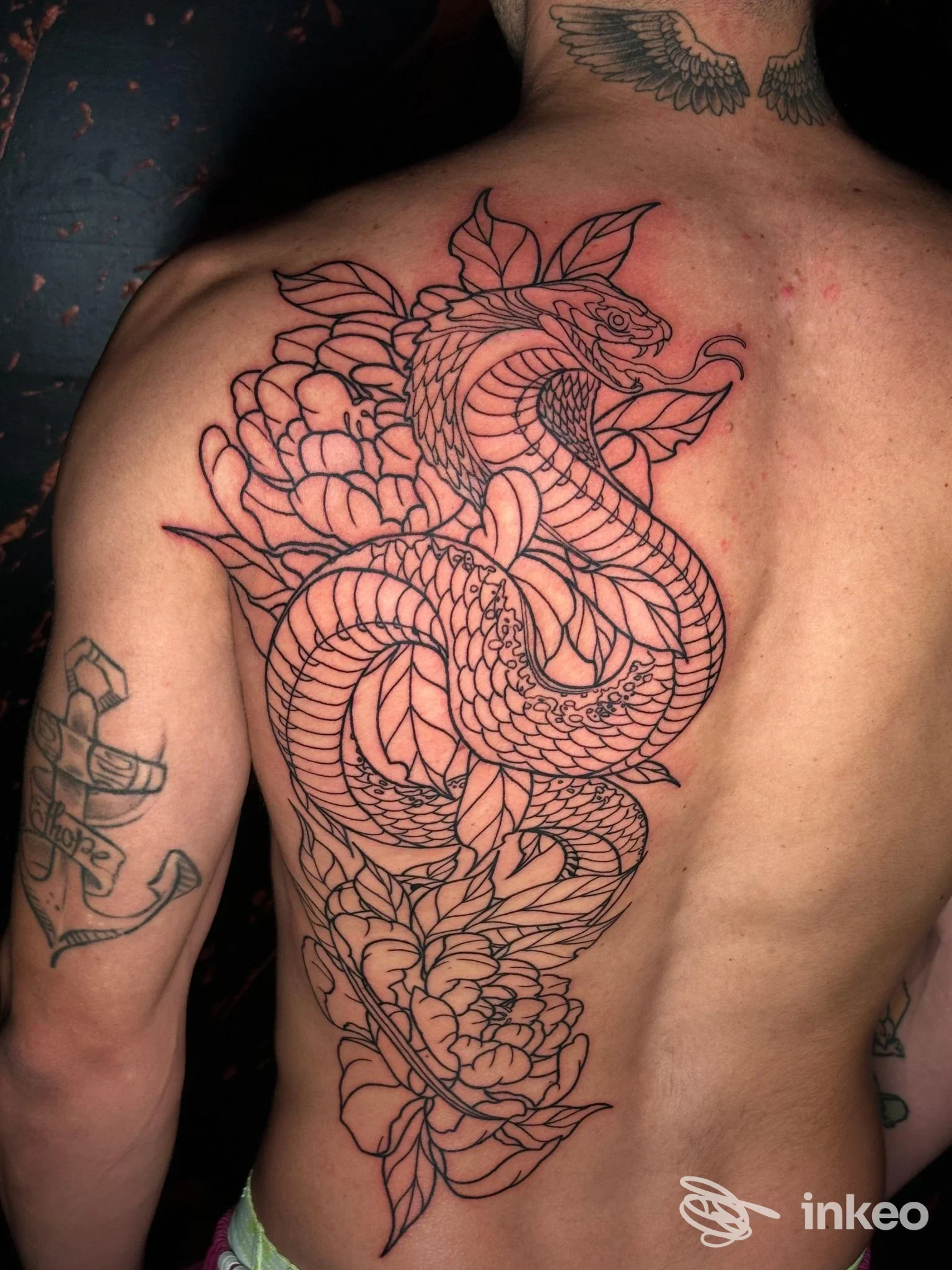 Grande tatuaggio a linee nere di un serpente e fiori sulla schiena di un uomo, foto realizzata presso AM_Tattoo Studio, Montemurlo.