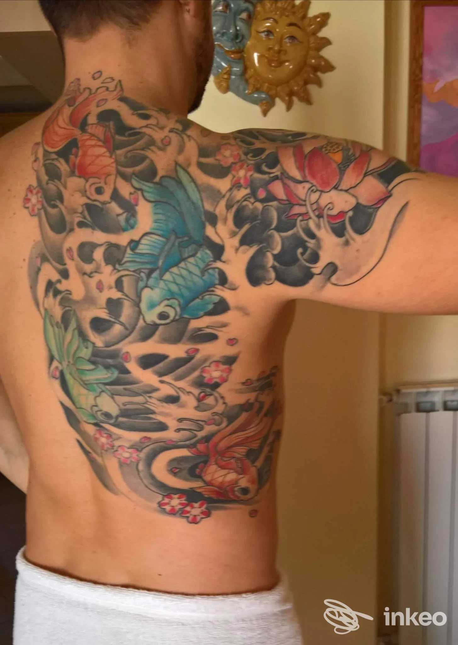 Grande tatuaggio colorato di carpe e fiori sulla schiena e spalla destra, foto condivisa dallo studio Admiral Tattoo a Massa.