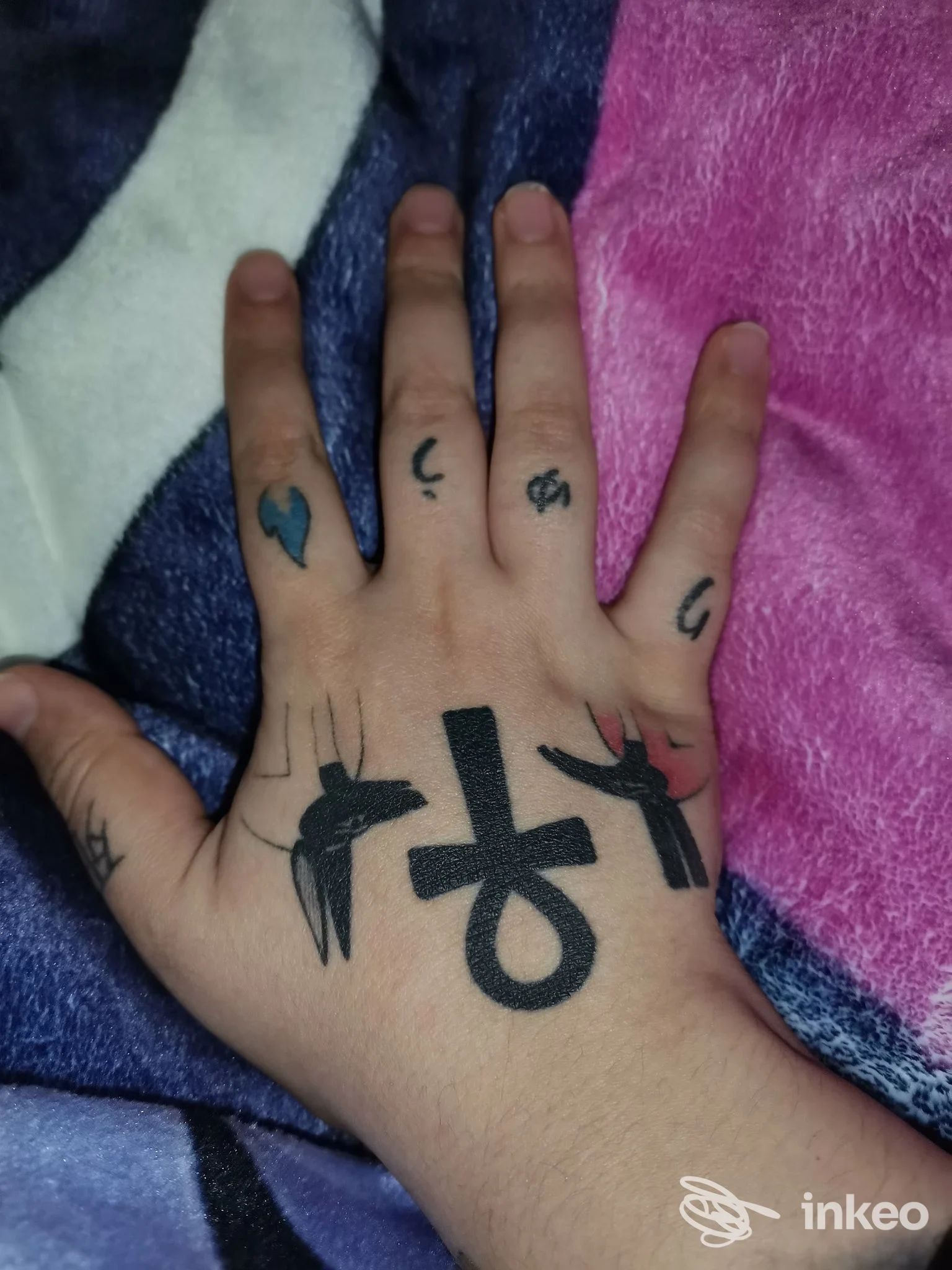 Dorso della mano tatuato con simbolo centrale e uccelli stilizzati, foto fornita dallo studio Afiordipelle Tattoo ad Arezzo.