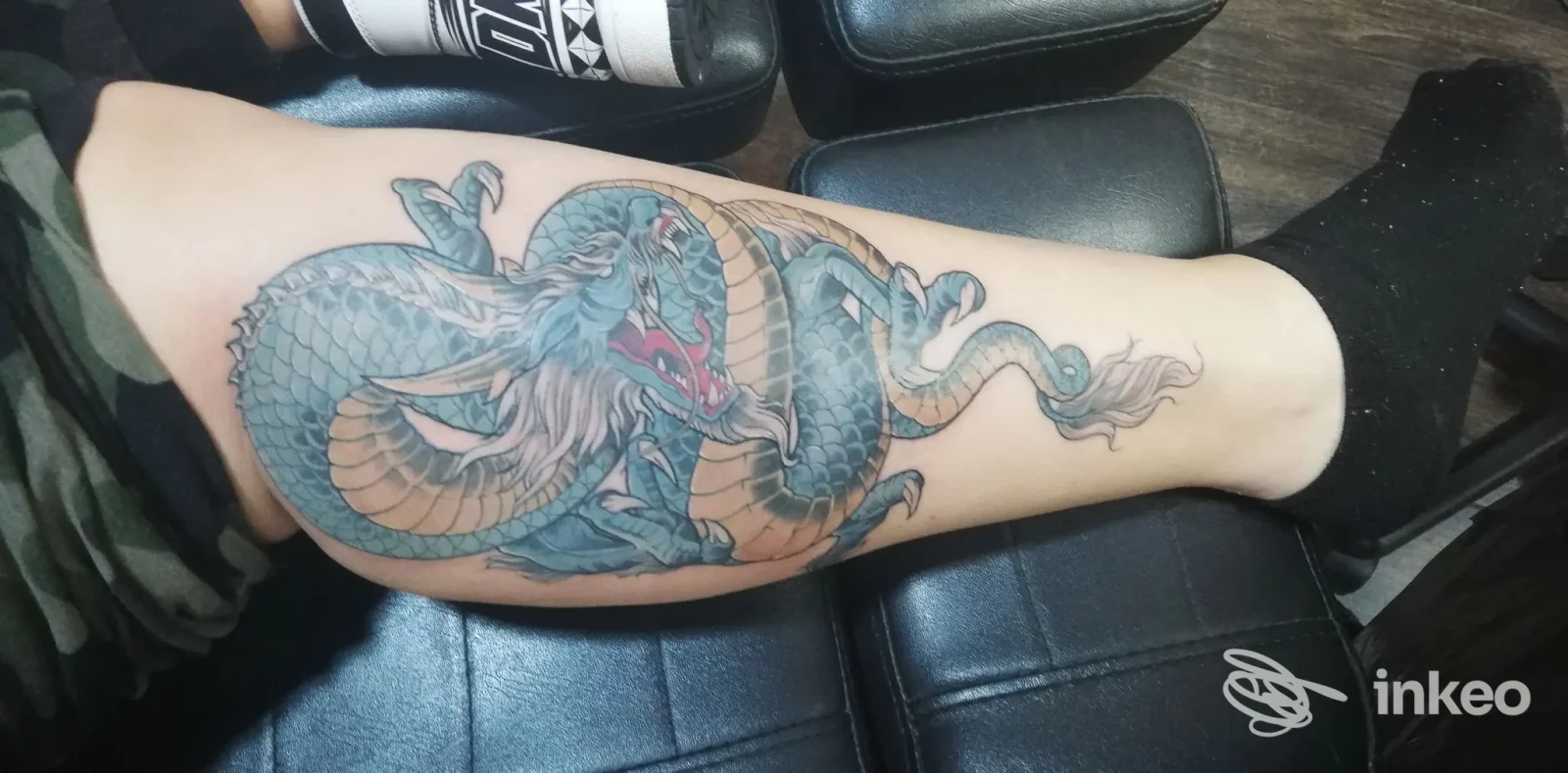 Polpaccio con grande tatuaggio a drago in toni verdi/blu, foto inviata dallo studio Afiordipelle Tattoo di Arezzo.