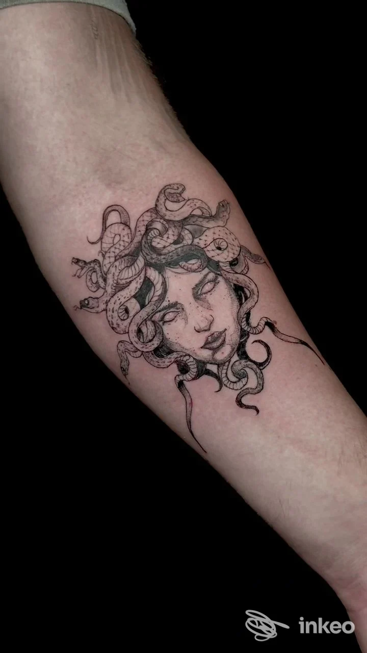 Tatuaggio stilizzato raffigurante la testa di Medusa in nero sull'avambraccio, con linework e puntinato ben definiti; foto dallo studio Alex Alvarez Tattoo Shop a Firenze.