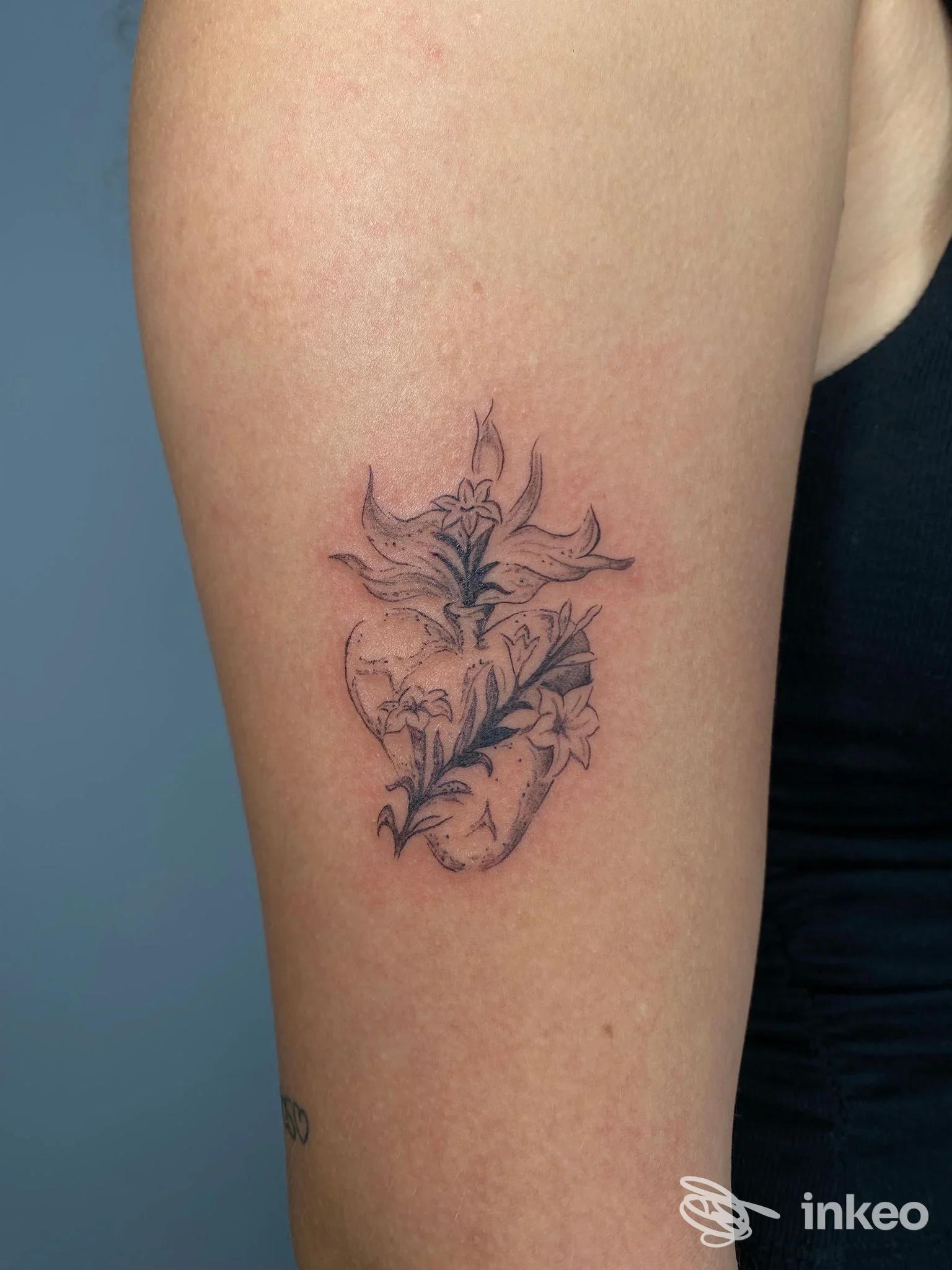 Delicato tatuaggio floreale in bianco e nero sul braccio superiore, realizzato da Abra tattoo Firenze a Firenze.
