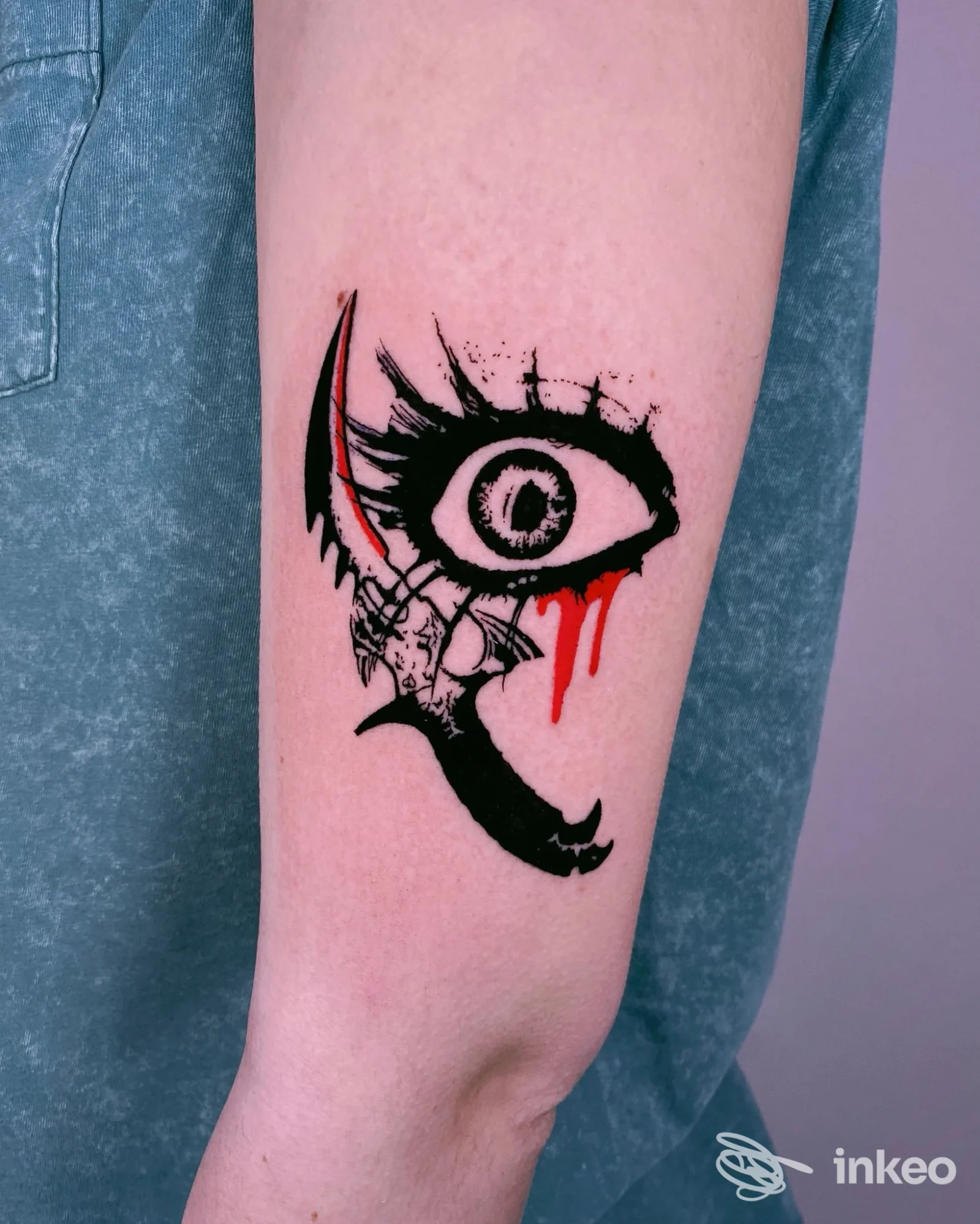 Tatuaggio sull'avambraccio con occhio stilizzato nero e schizzi rossi; foto di Abra tattoo Firenze, Firenze.
