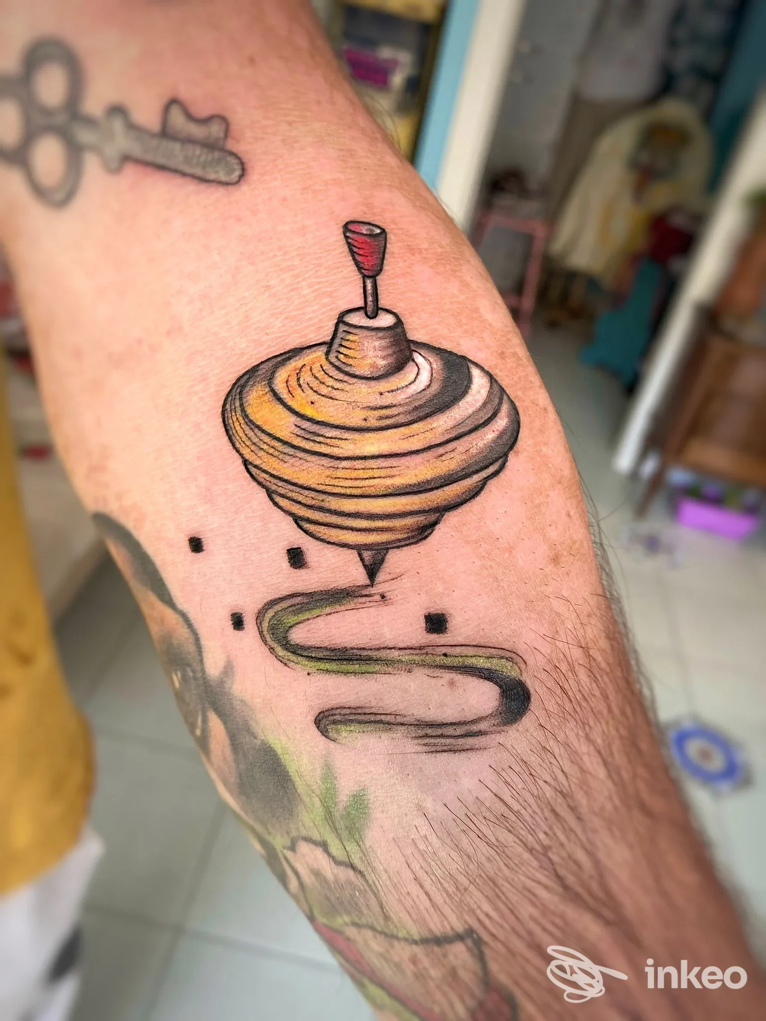 Tatuaggio a forma di trottola colorata sull'avambraccio, Art Mess tattoo, Molino del Piano.