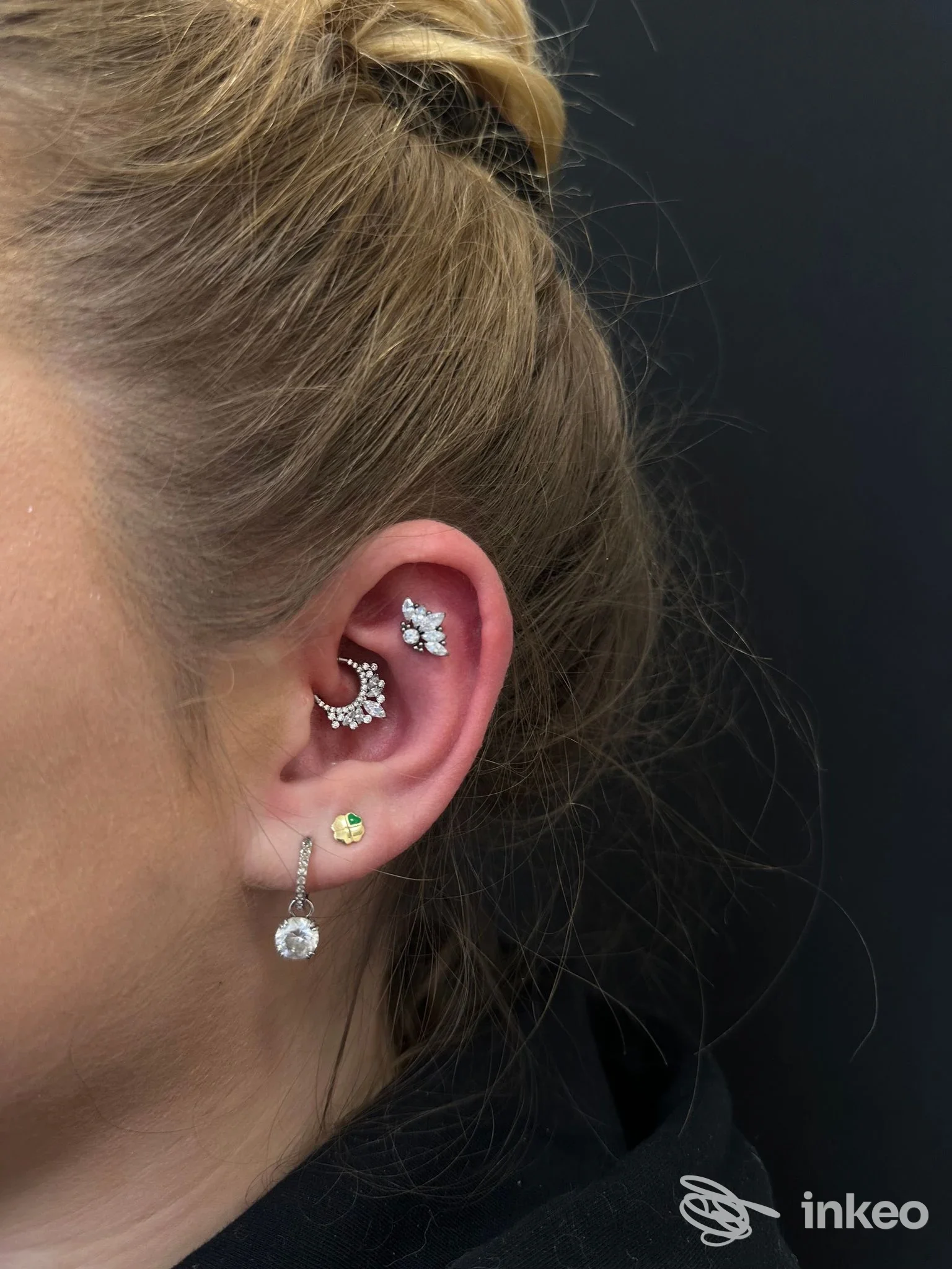 Orecchio con più piercing gioiello visibili su sfondo nero, foto del lavoro eseguito da Busybee Tattoo and Piercing a Empoli.