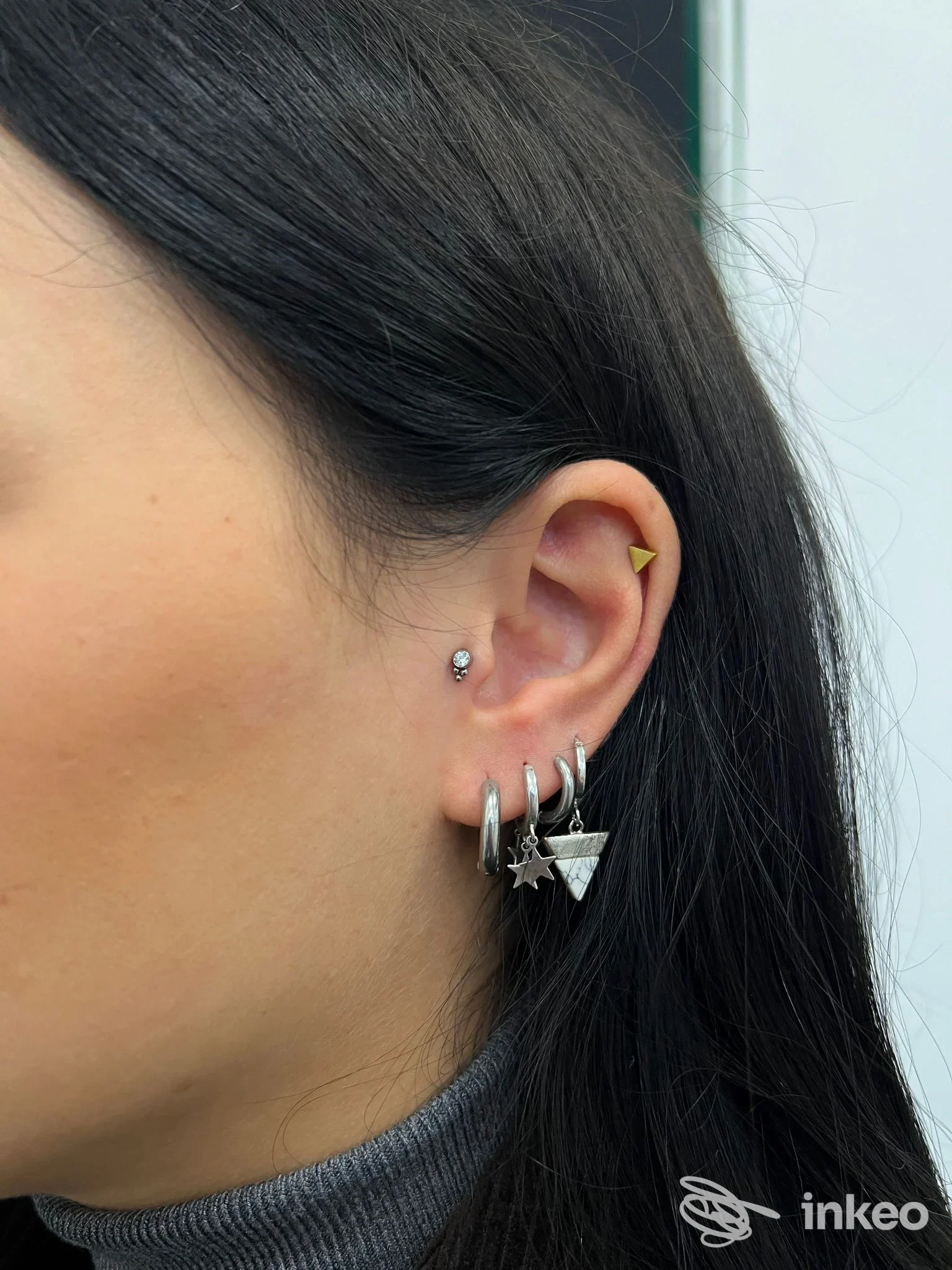 Primo piano di un orecchio con diversi piercing al lobo ed elice, foto per Busybee Tattoo and Piercing, Empoli.