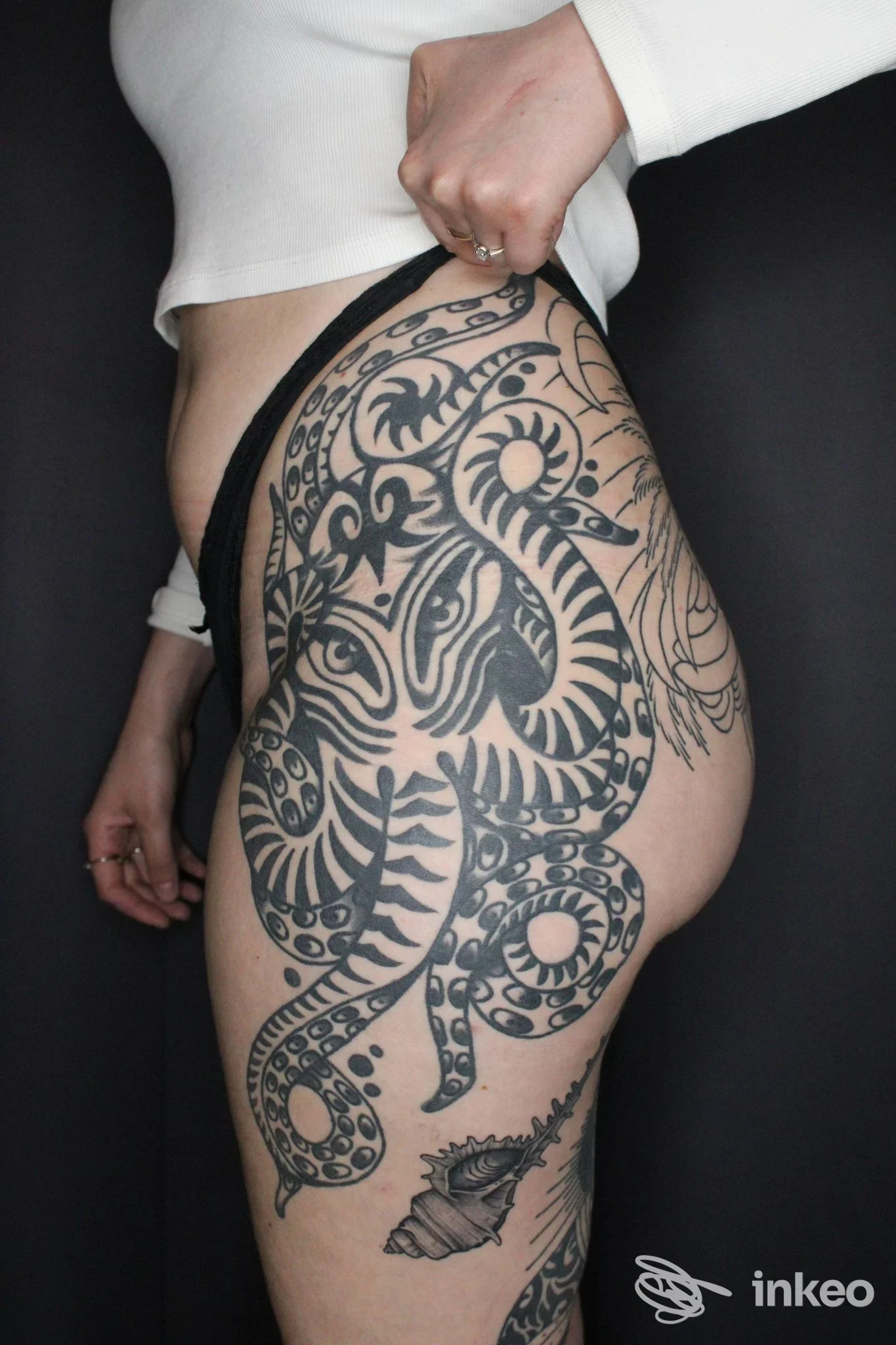 Ampio tatuaggio nero su fianco e coscia, foto a figura intera del torso inferiore per Busybee Tattoo and Piercing, Empoli.