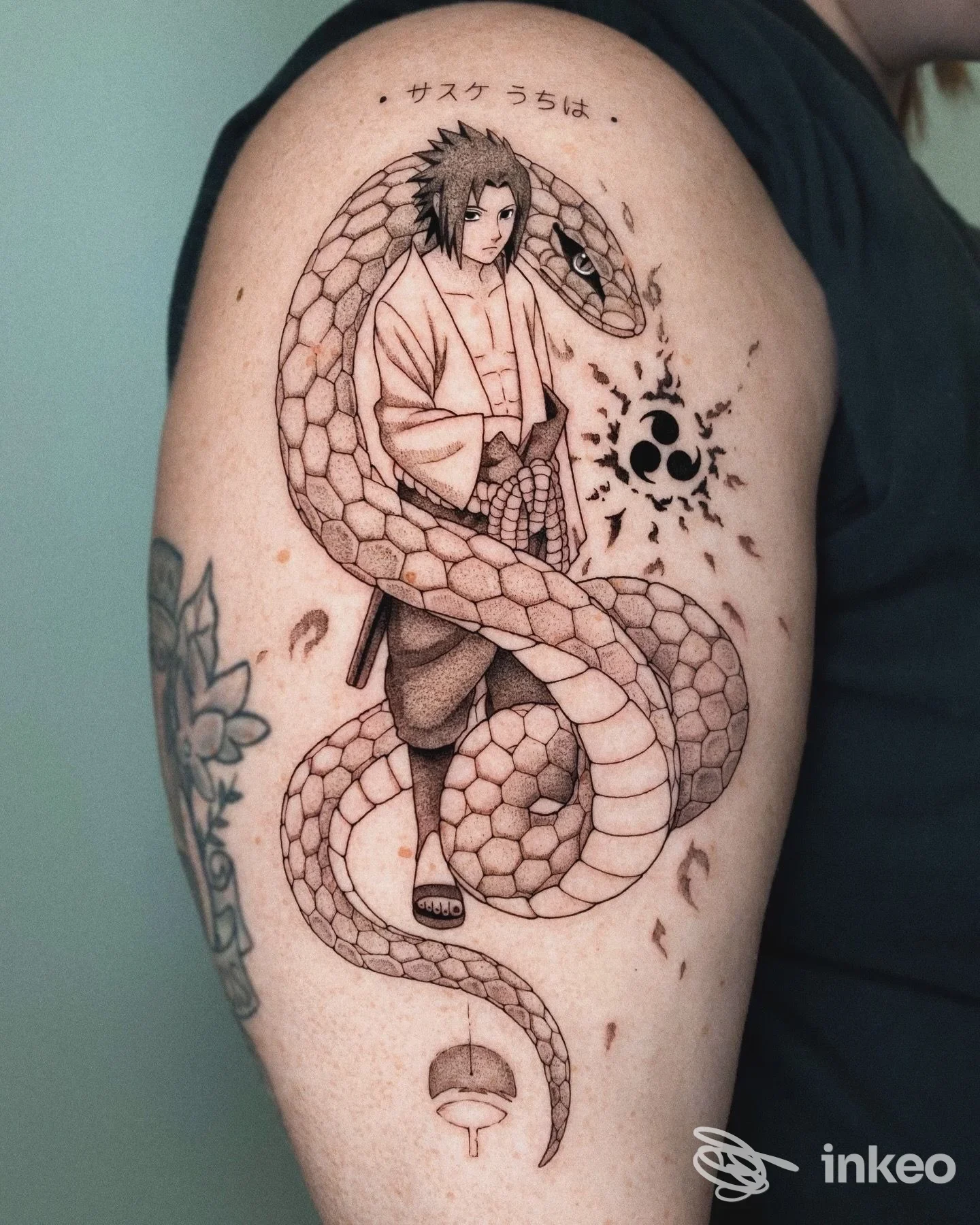 Grande tatuaggio su omero raffigurante un personaggio anime avvolto da un serpente; immagine fornita da Cadillac Ranch Tattoo, Firenze.