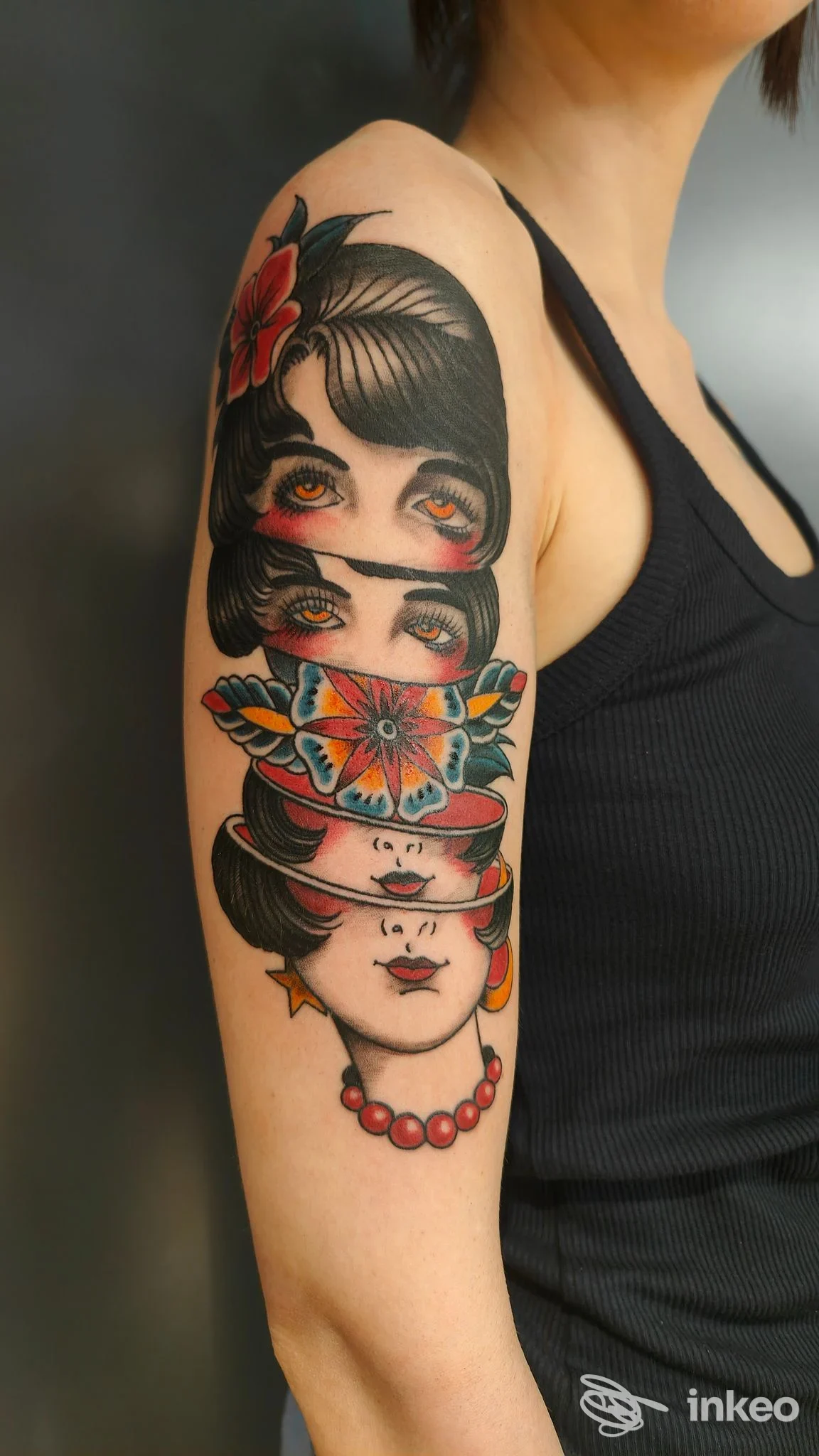 Tatuaggio colorato su braccio superiore con volti sovrapposti e fiori, Cherry Red Tattoo & Body Piercing, Empoli.