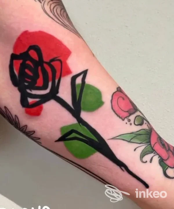 Tatuaggio a stelo e fiore con campiture rosse e verdi sull'avambraccio, Con Safos Tattoo, Ponsacco.