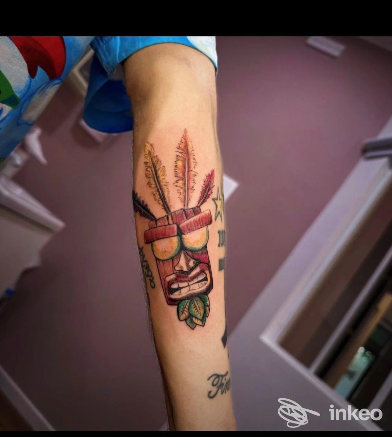 Tatuaggio colorato su avambraccio con maschera tribale e piume, foto fornita da DATE TATTOO STUDIO, Sansepolcro.