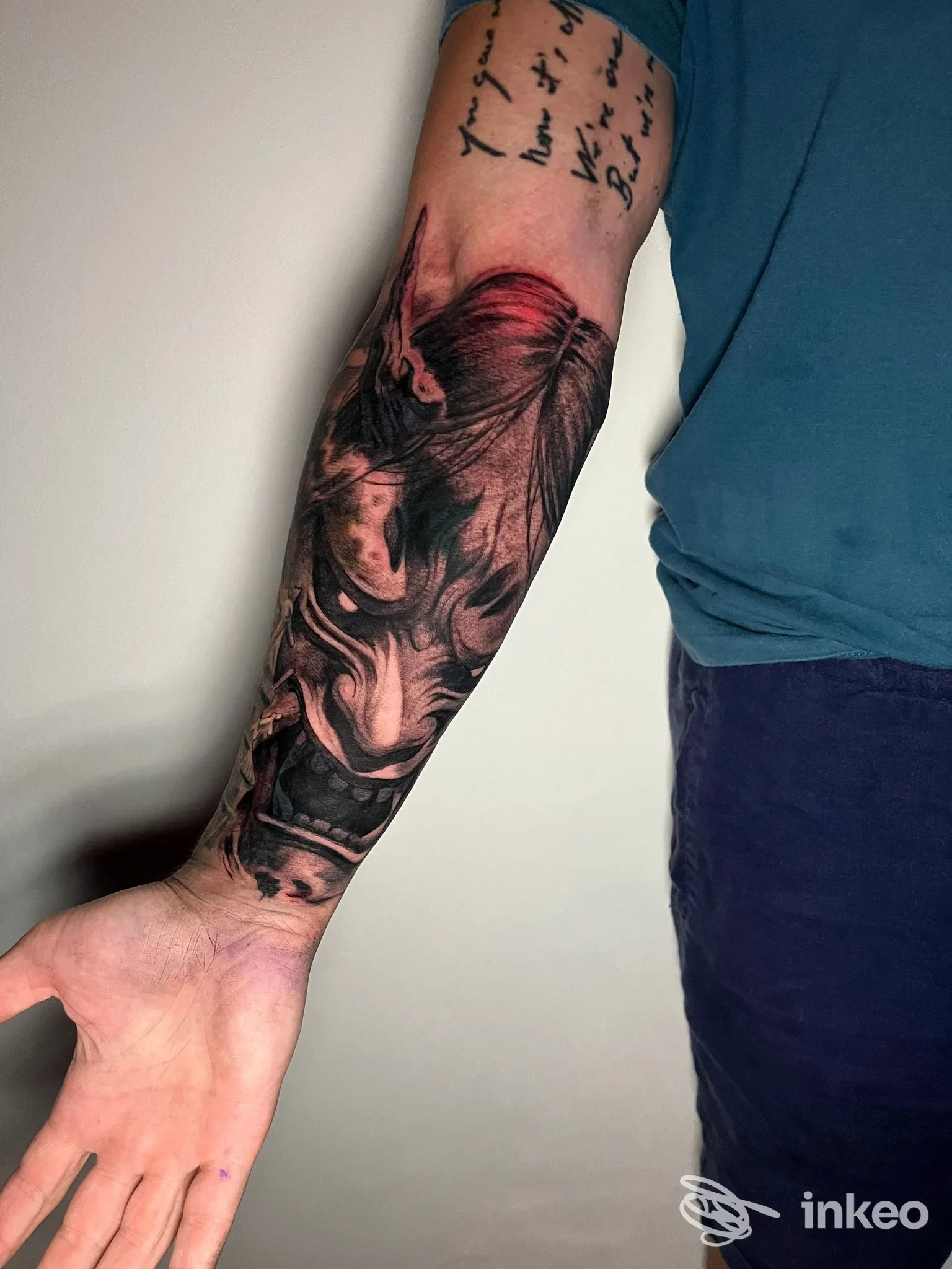 Tatuaggio a manica sull'avambraccio destro con volti realistici in nero e tocchi rossi, DAIMON tattoo & art factory, Lucca.
