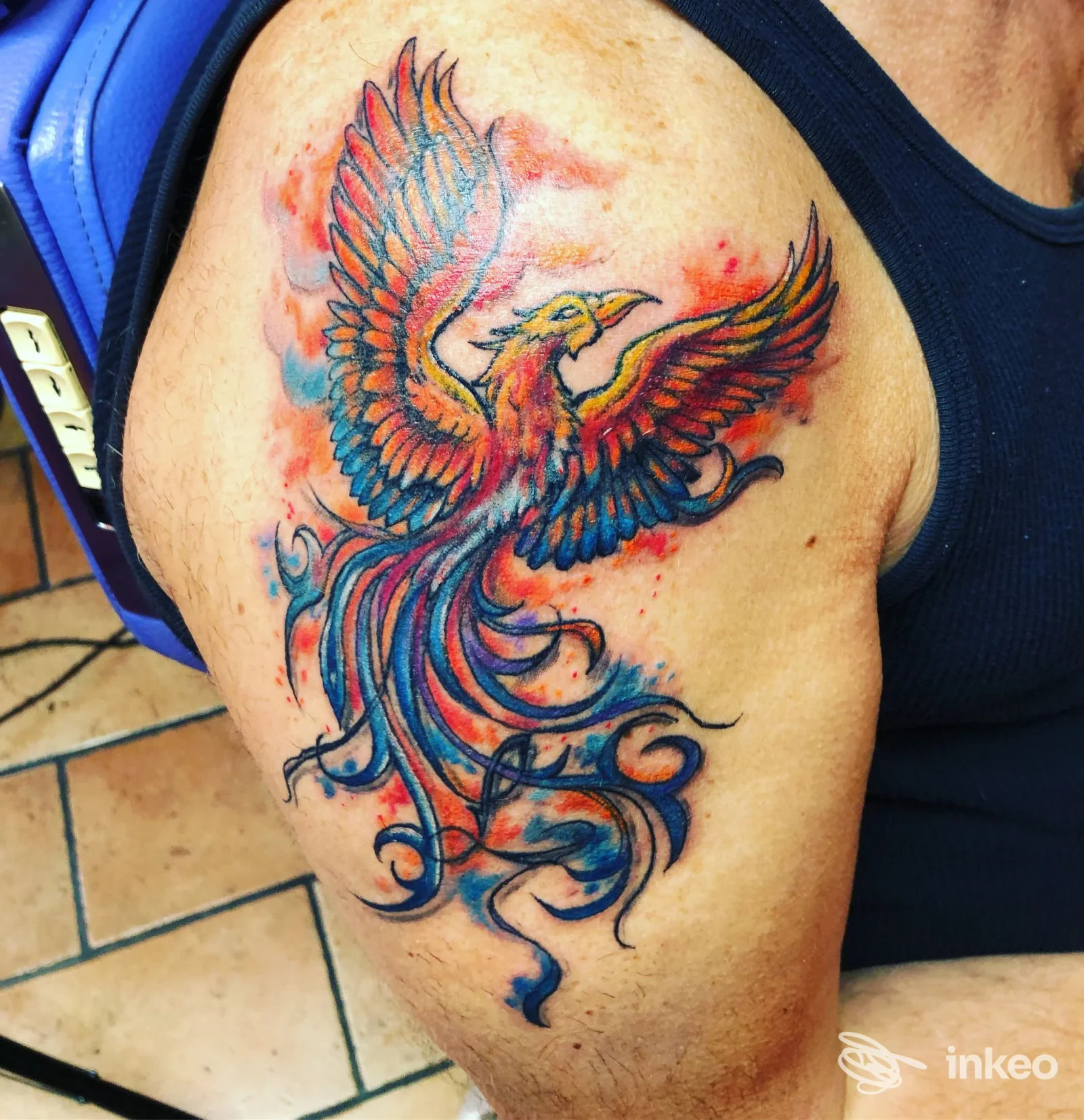 Tatuaggio fenice colorata sulla spalla, fotografia di Freedom Tattoo a Pistoia che mostra dettagli e colori vividi.