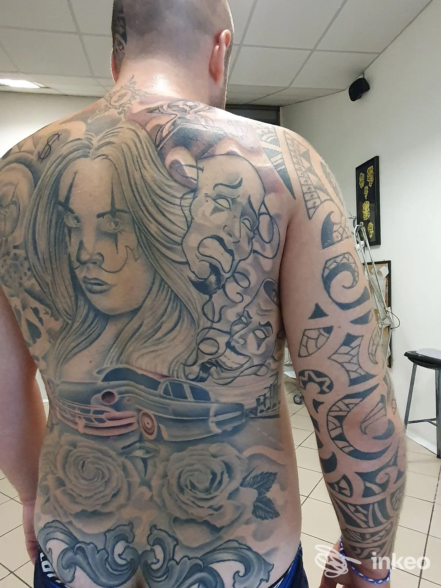 Uomo di schiena con ampio tatuaggio black-and-grey su schiena e braccio, fotografia dallo studio I.K.T TATTOO a Pistoia.